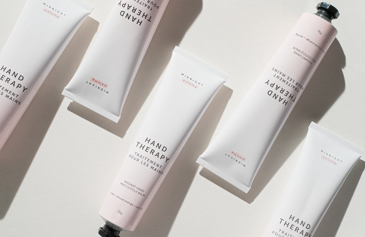 Five tubes of Hand Therapy Cream featuring Blood Orange and Vanilla scent on a soft background.