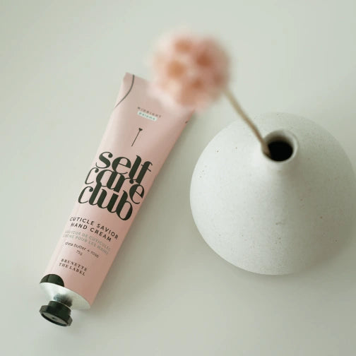 Midnight Paloma x Brunette the Label Cuticle Savior Hand Cream tube next to a white vase on a light background