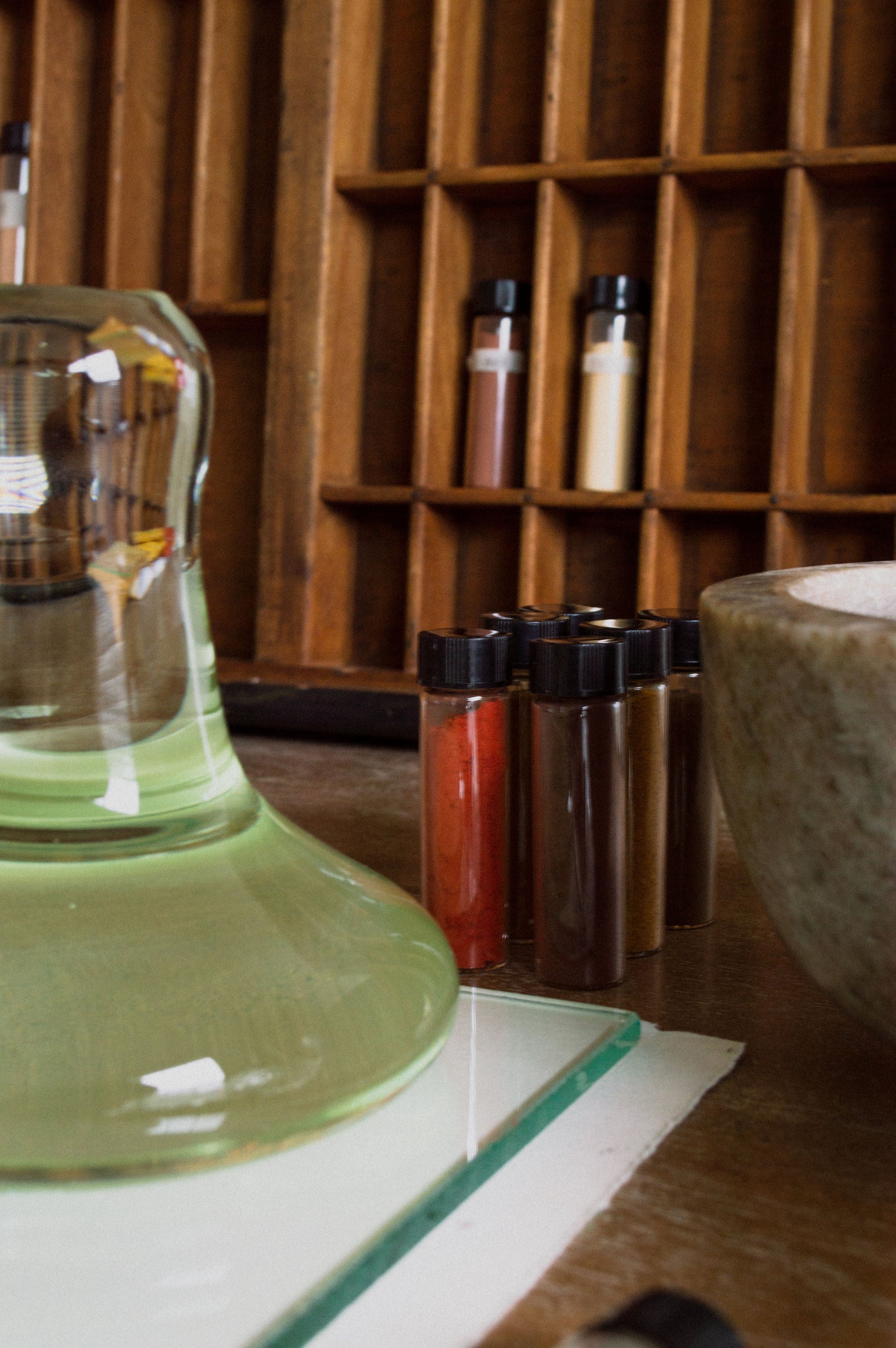 Spices and a Clear Glass Paint Muller  on a wooden shelf