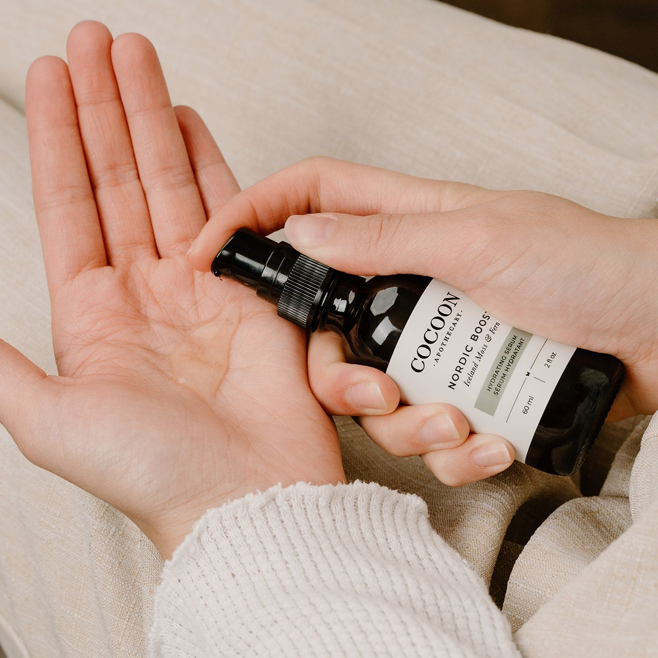 Person holding a small bottle labeled 'Cocoon Nordic Roots' over another hand.