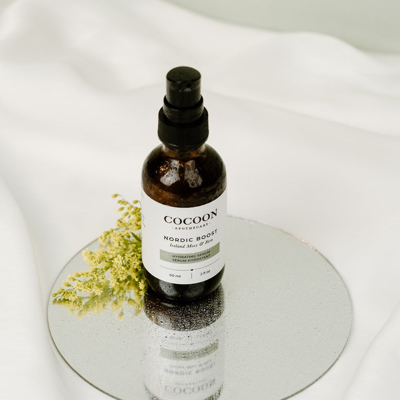 Cocoon skincare bottle on a white surface with a small plant