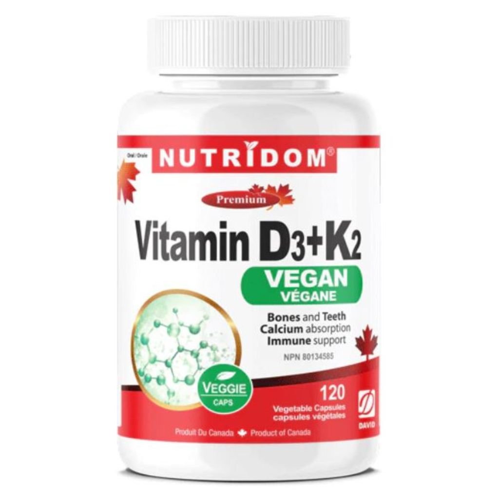 A white plastic bottle of NutriDom Vitamin D3+K2 veggie capsules, featuring a white label with red and green accents, on a plain white background.