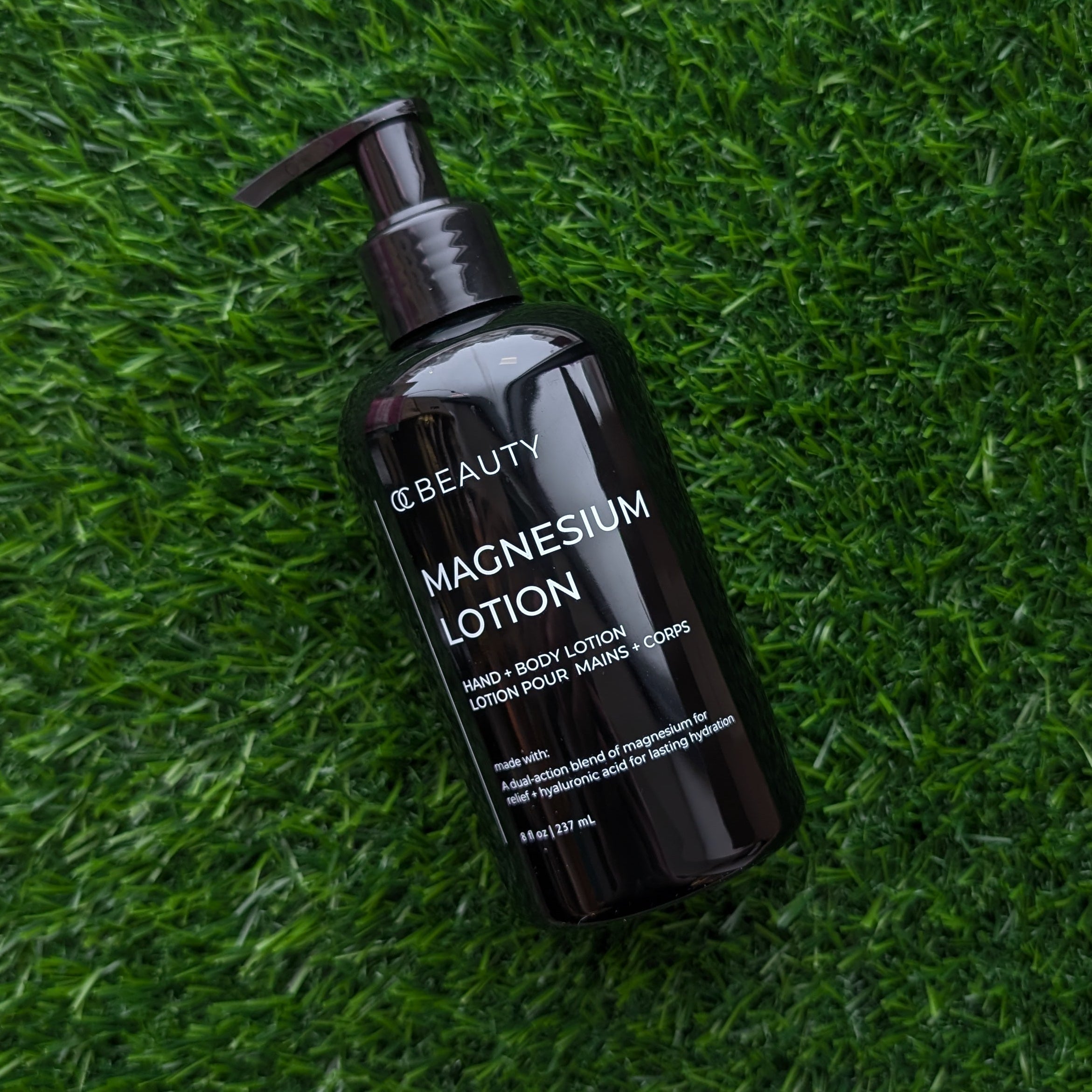 Black bottle of OC Beauty Magnesium Hand & Body Lotion on green grass