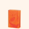 Orange soap bar with a leaf design on a white background