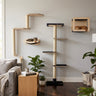 A tall cat tree with multiple platforms and a cubby shelf is shown in a styled living room setting with a gray sofa, plants, and two cats resting on and inside the cat tree.