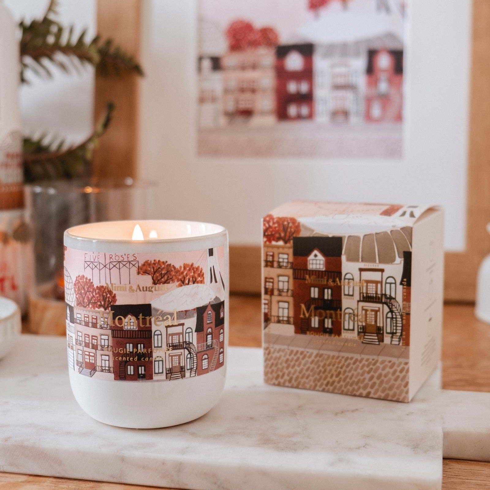 Candle with a decorative design on a marble surface, with a blurred background of a house illustration.