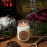 Candle labeled 'Ontario Woods' on a wooden surface with decorative elements. Stop and Smell the Candles