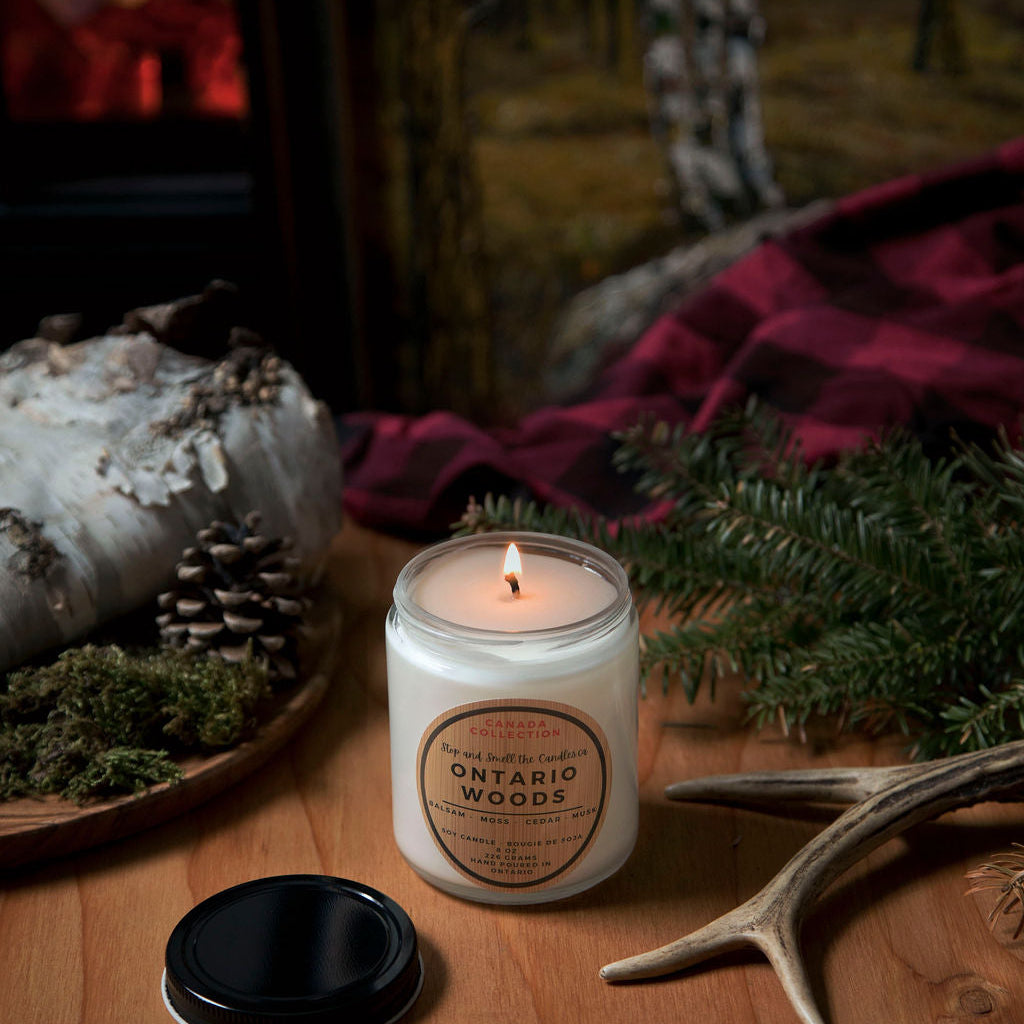 Candle labeled 'Ontario Woods' on a wooden surface with natural elements
