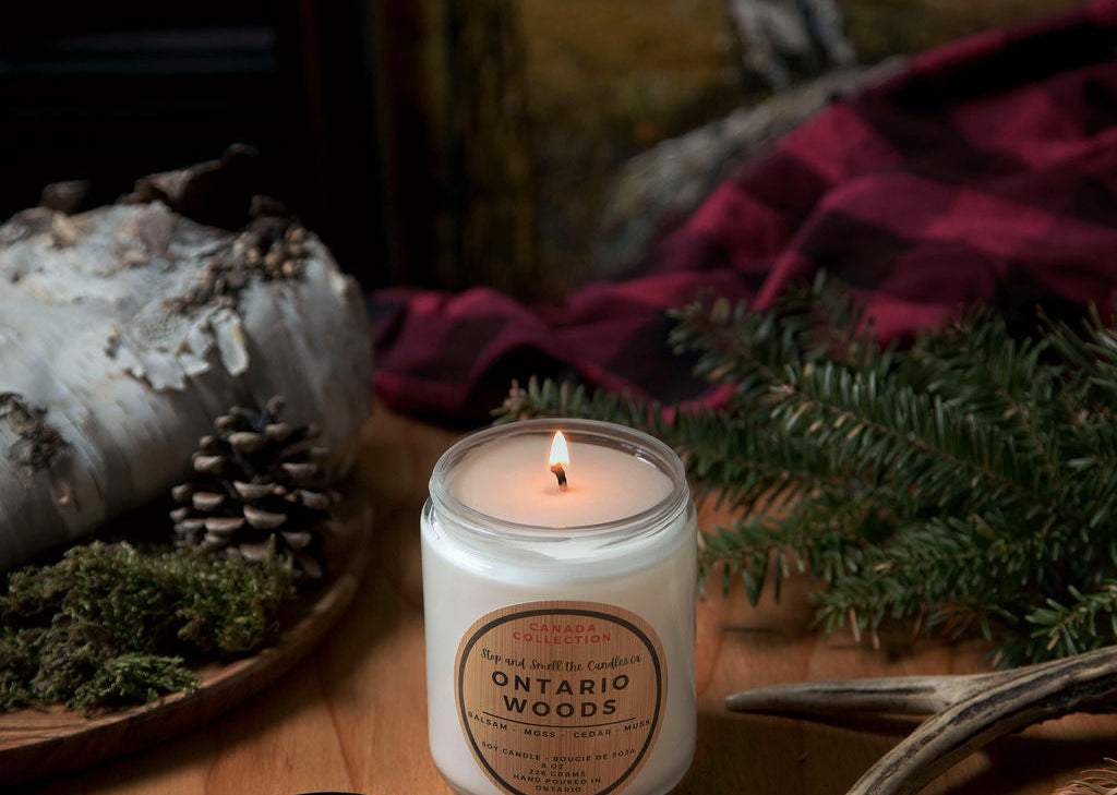 Candle labeled 'Ontario Woods' on a wooden surface with natural elements