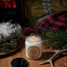 Candle labeled 'Ontario Woods' on a wooden surface with natural elements