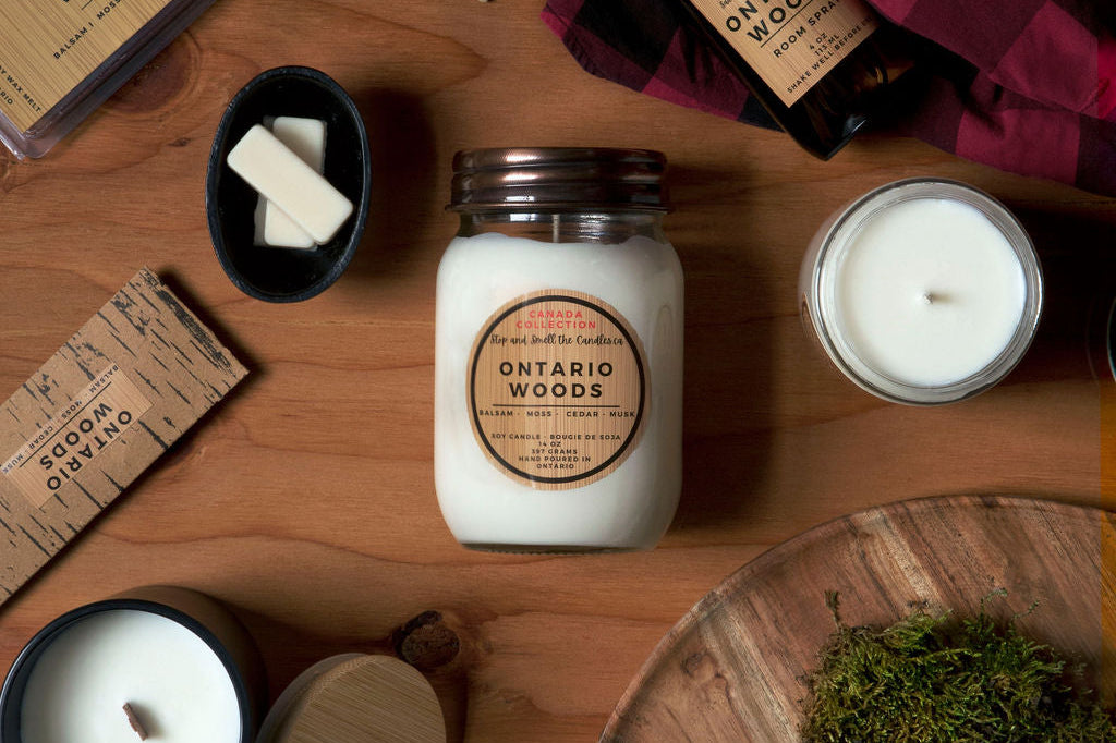 Collection of candles and products with 'Ontario Woods' branding on a wooden surface.
