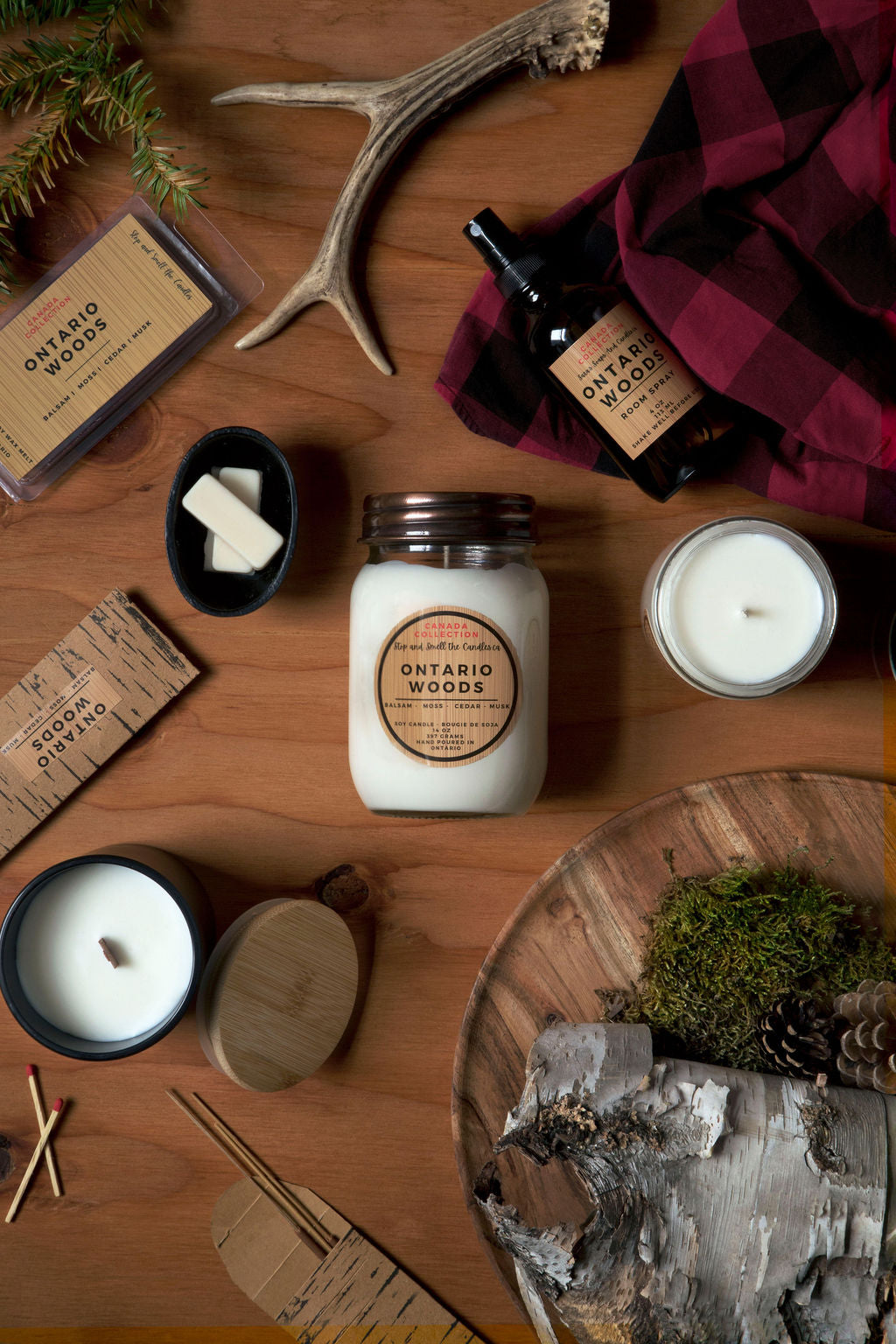 Collection of candles and products with 'Ontario Woods' branding on a wooden surface.
