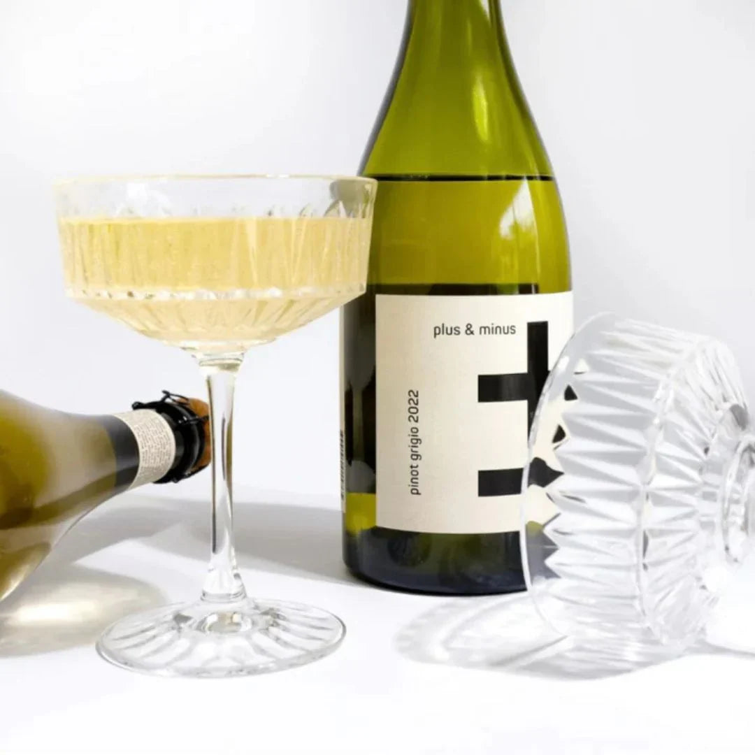 Wine bottle labeled 'plus & minus' with a glass of white wine on a white background  The Sobr Market