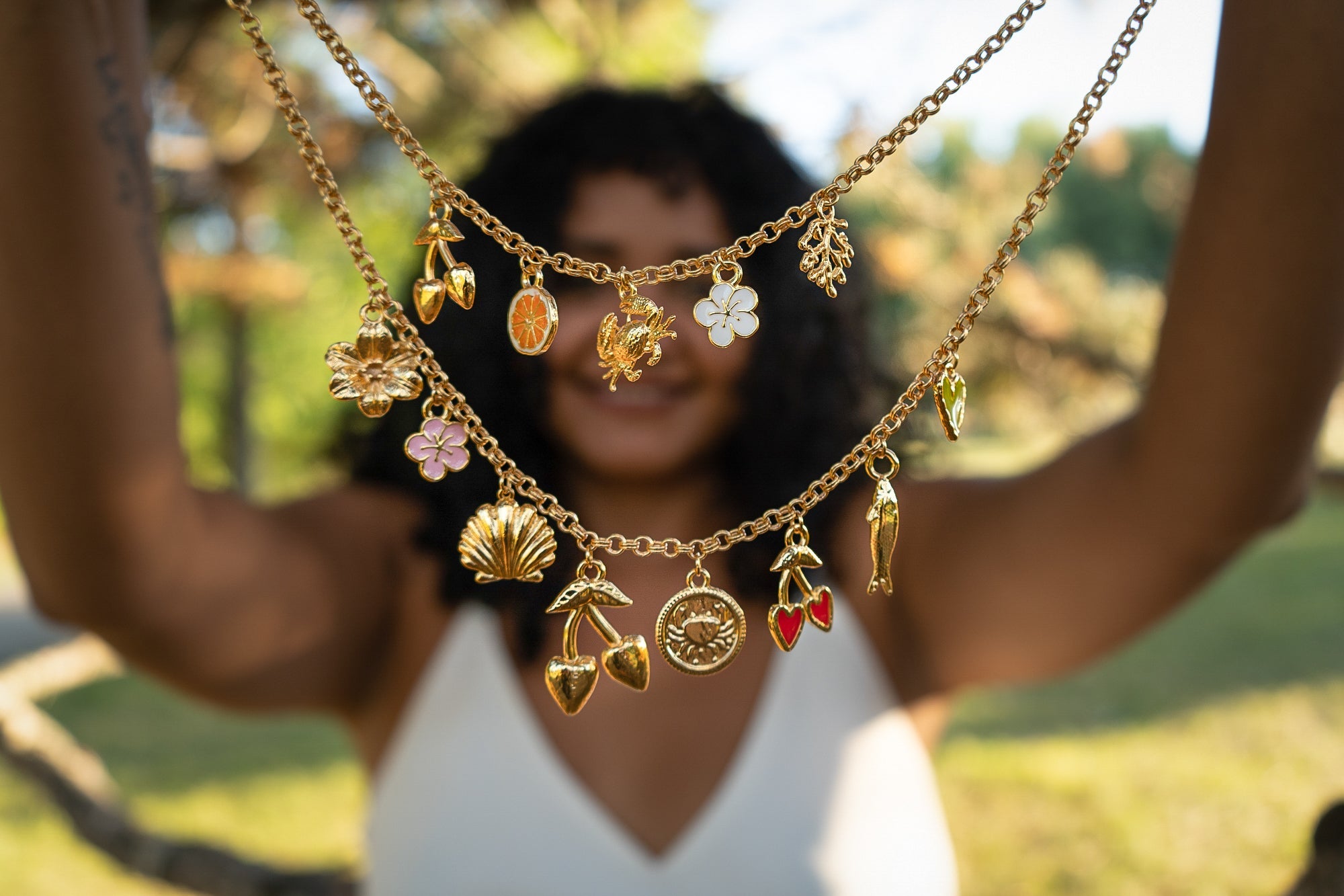 Woman holding a Coastal Crush Necklace with various charms made by Pinky Mimosa