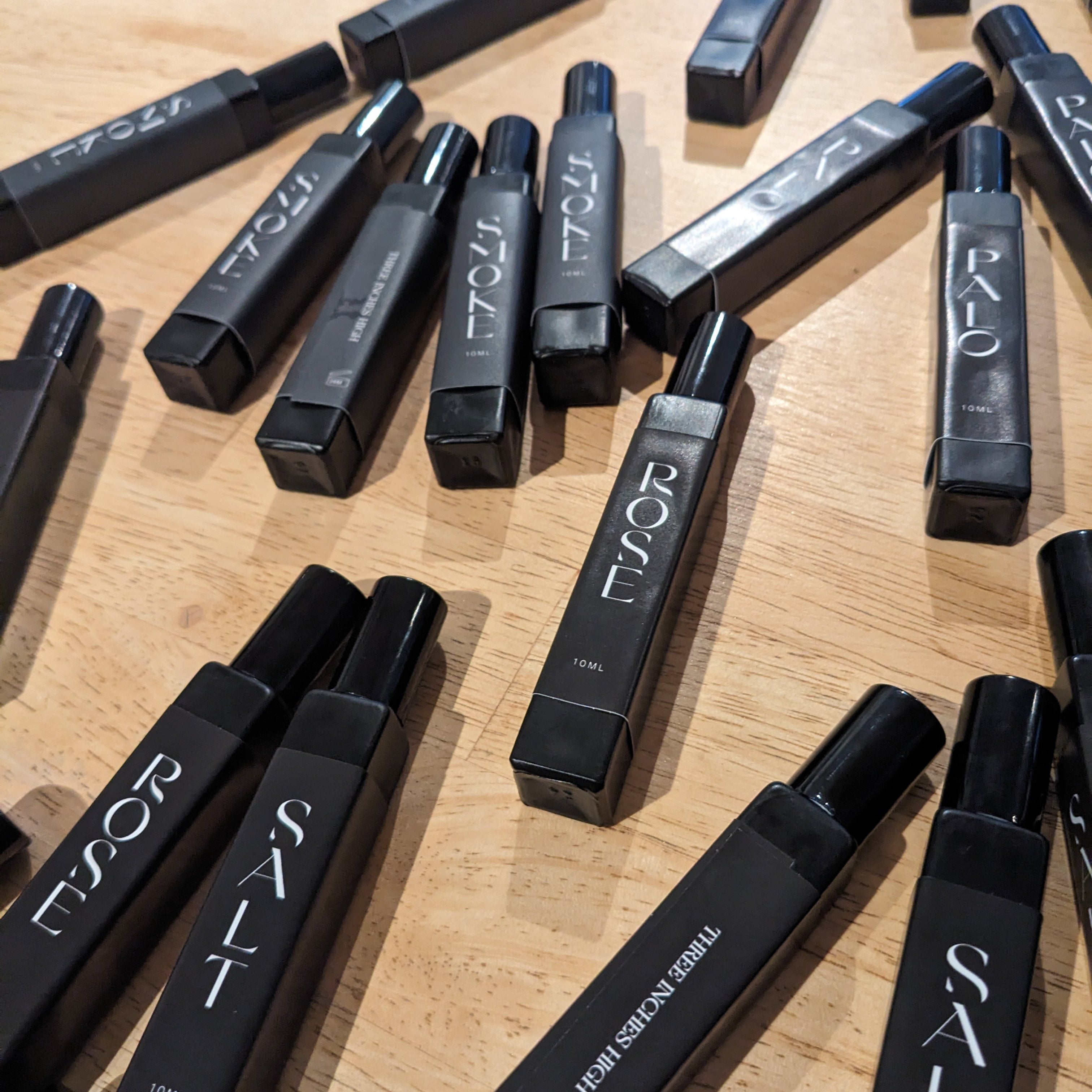 Black 10ml perfume roll on bottles with visible branding on a wooden surface