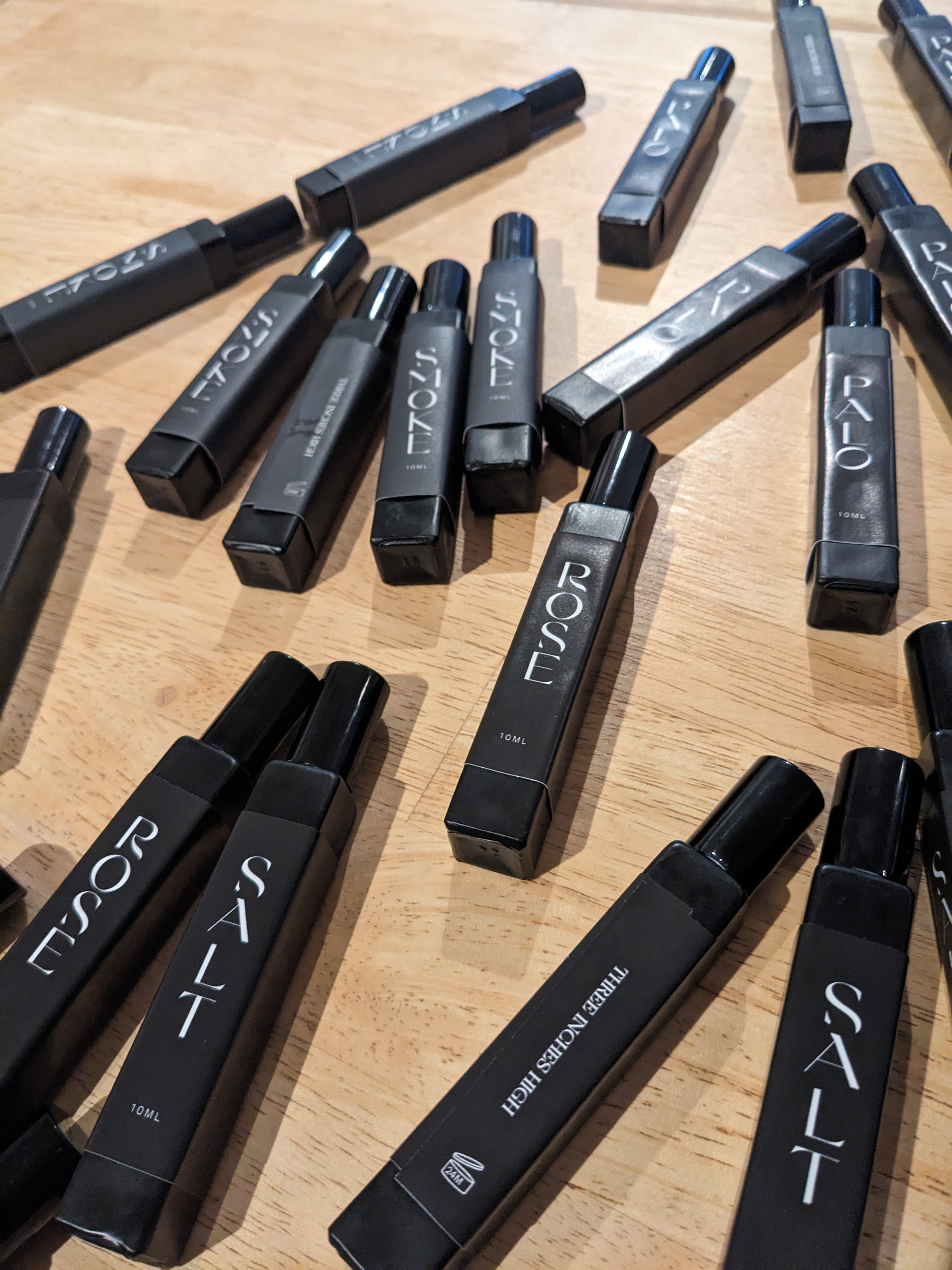 Black 10ml perfume roll on bottles with visible branding on a wooden surface