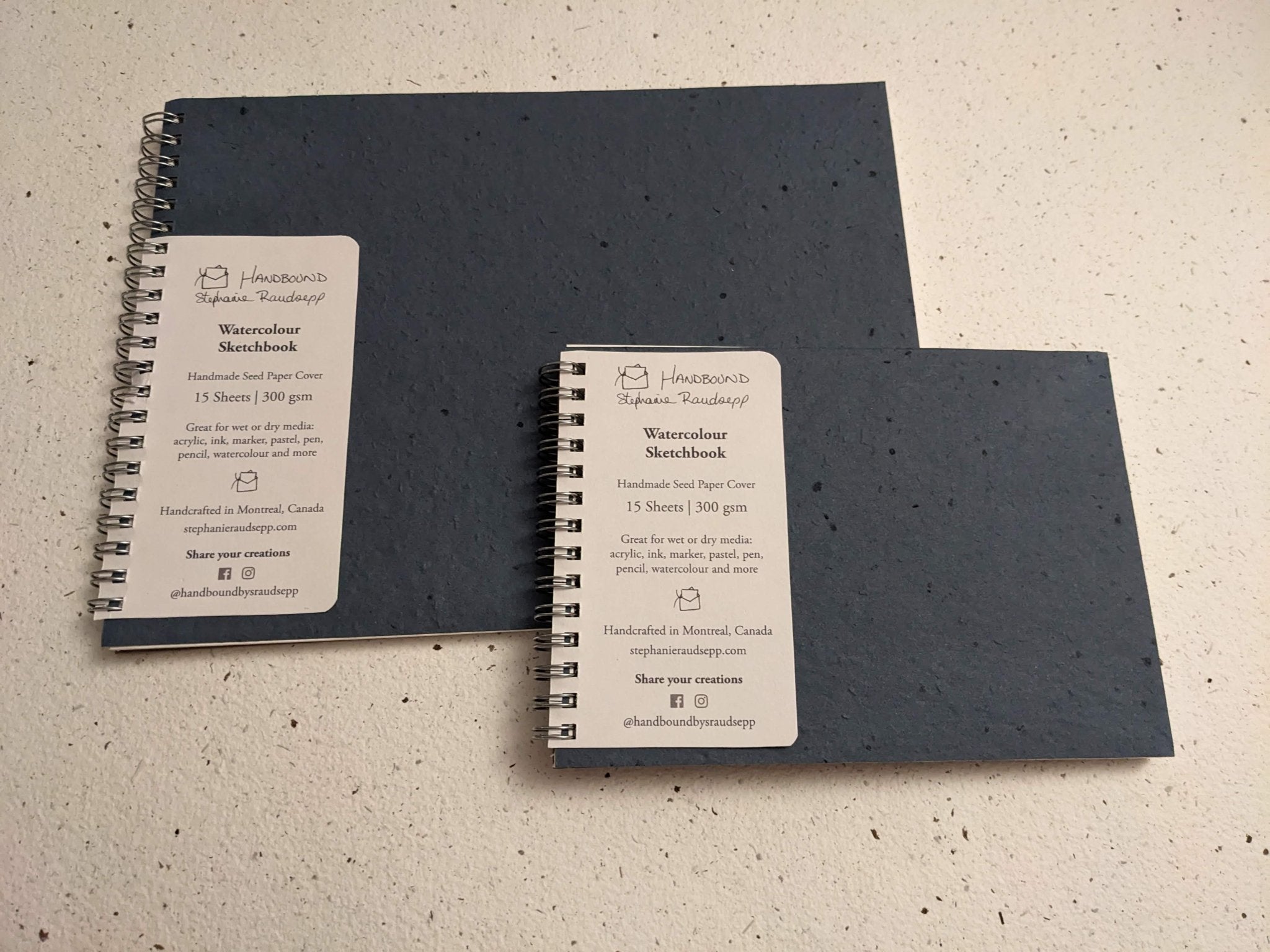 Two black spiral-bound sketchbooks with labels Large Plantable Watercolour Sketchbook by Creative Artifacts HQ
