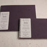 Two purple notebooks with white labels on a textured surface Plantable Watercolour Sketchbook by Creative Artifacts HQ