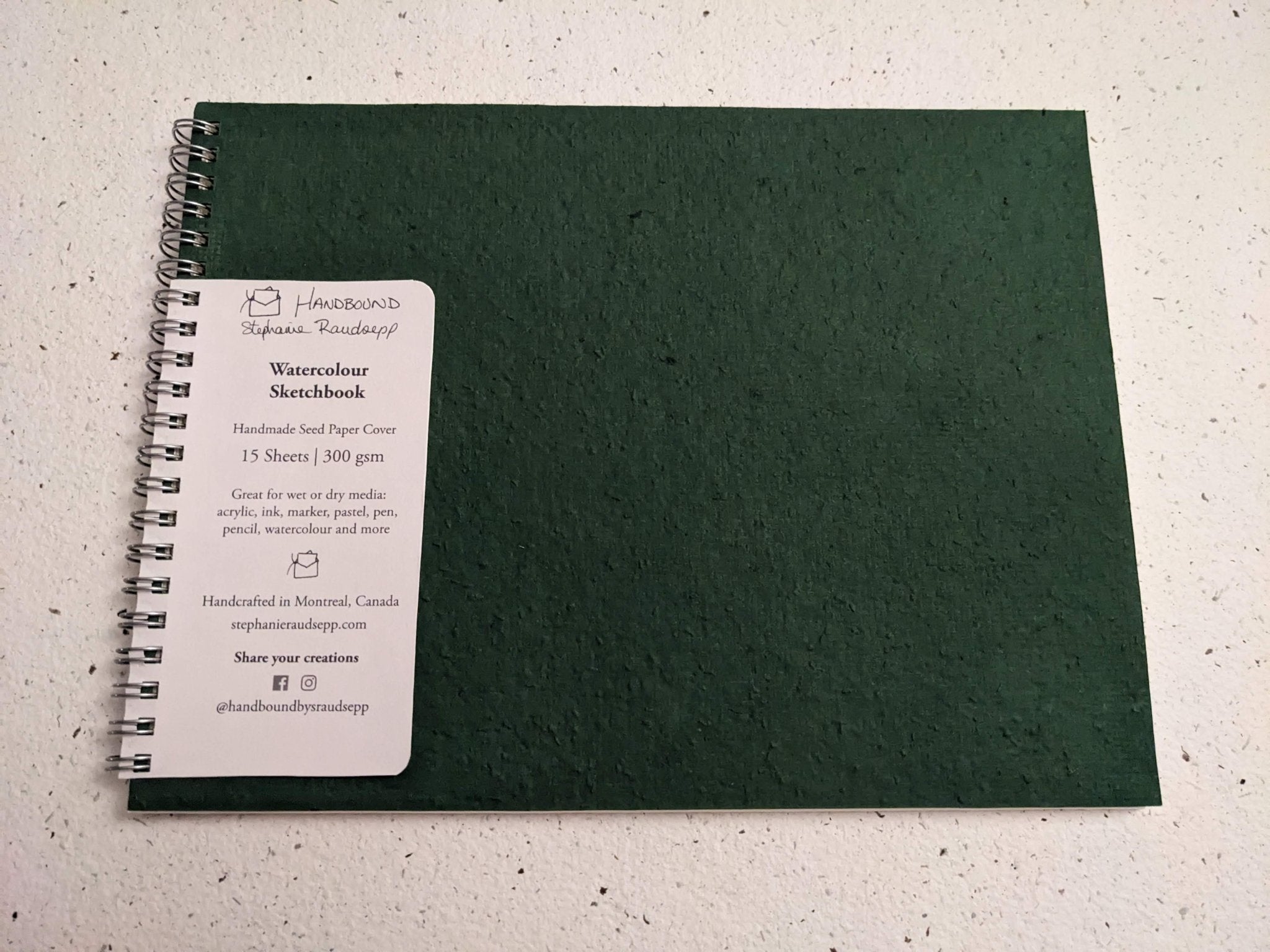 Green sketchbook with a label on a textured surface Plantable Watercolour Sketchbook by Creative Artifacts HQ