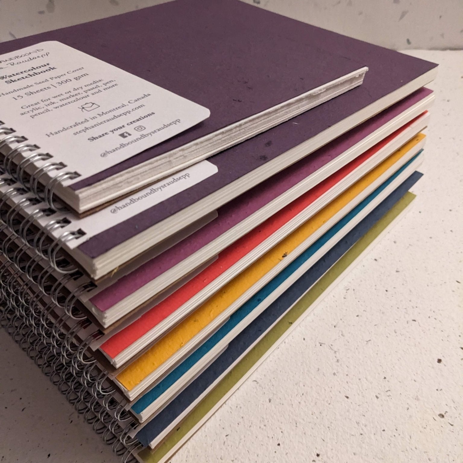 Stack of colorful notebooks on a textured surface Plantable Watercolour Sketchbook by Creative Artifacts HQ