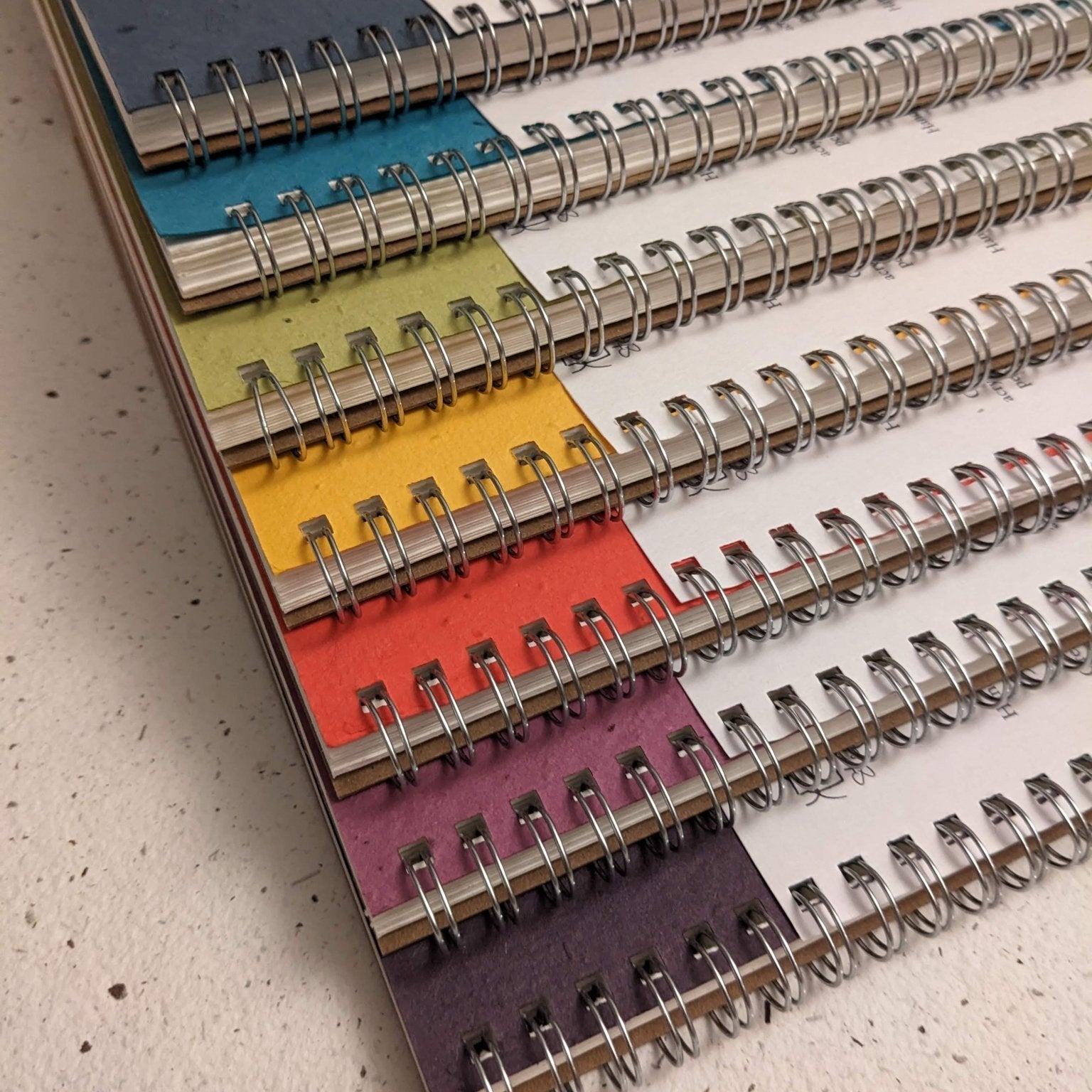 Colorful spiral-bound notebooks stacked on a textured surface Large Plantable Watercolour Sketchbook by Creative Artifacts HQ