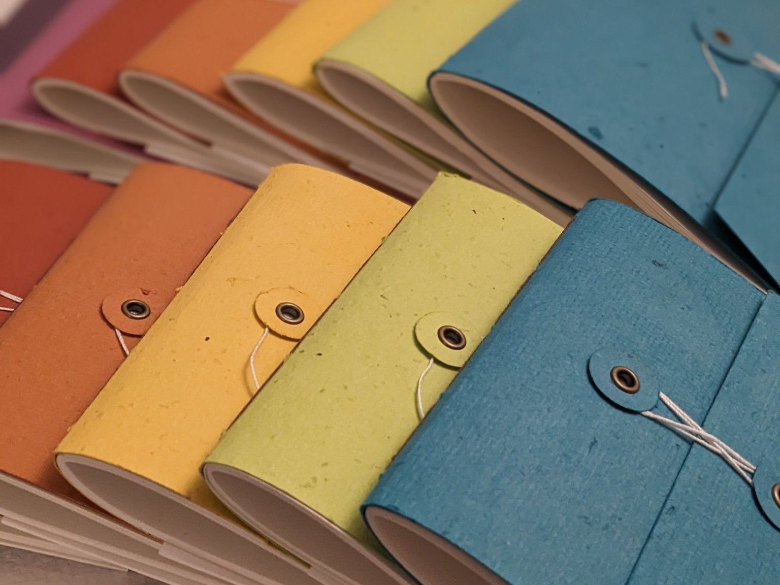 Colorful notebooks with fabric covers arranged on a light grey background Creative Artifacts HQ
