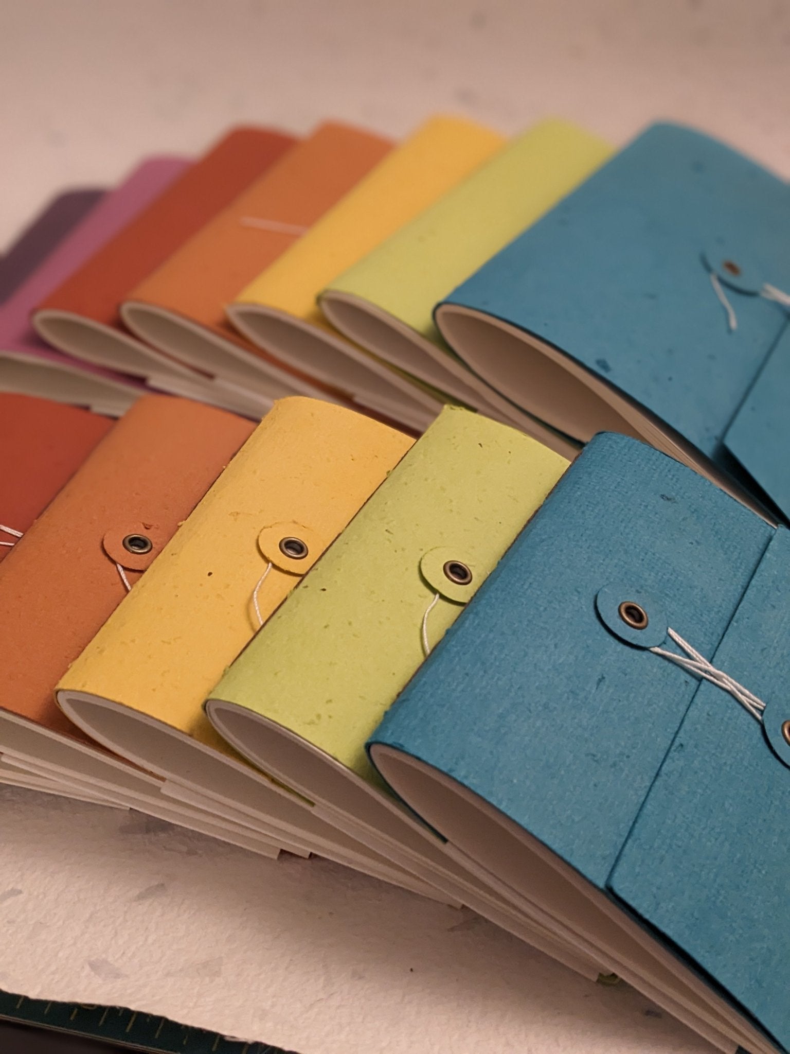 Colorful notebooks with fabric covers arranged on a light grey background Creative Artifacts HQ