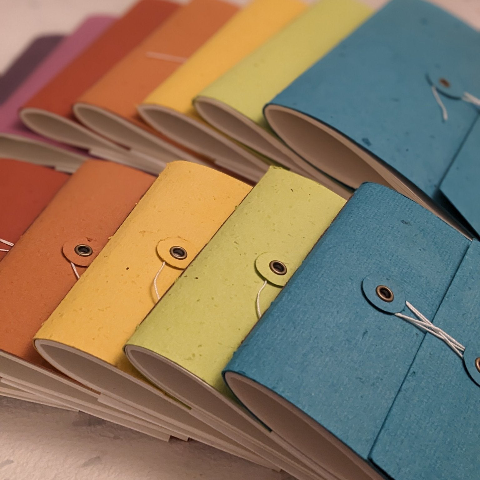 Colorful notebooks with fabric covers arranged on a light surface. Creative Artifacts HQ plantable 