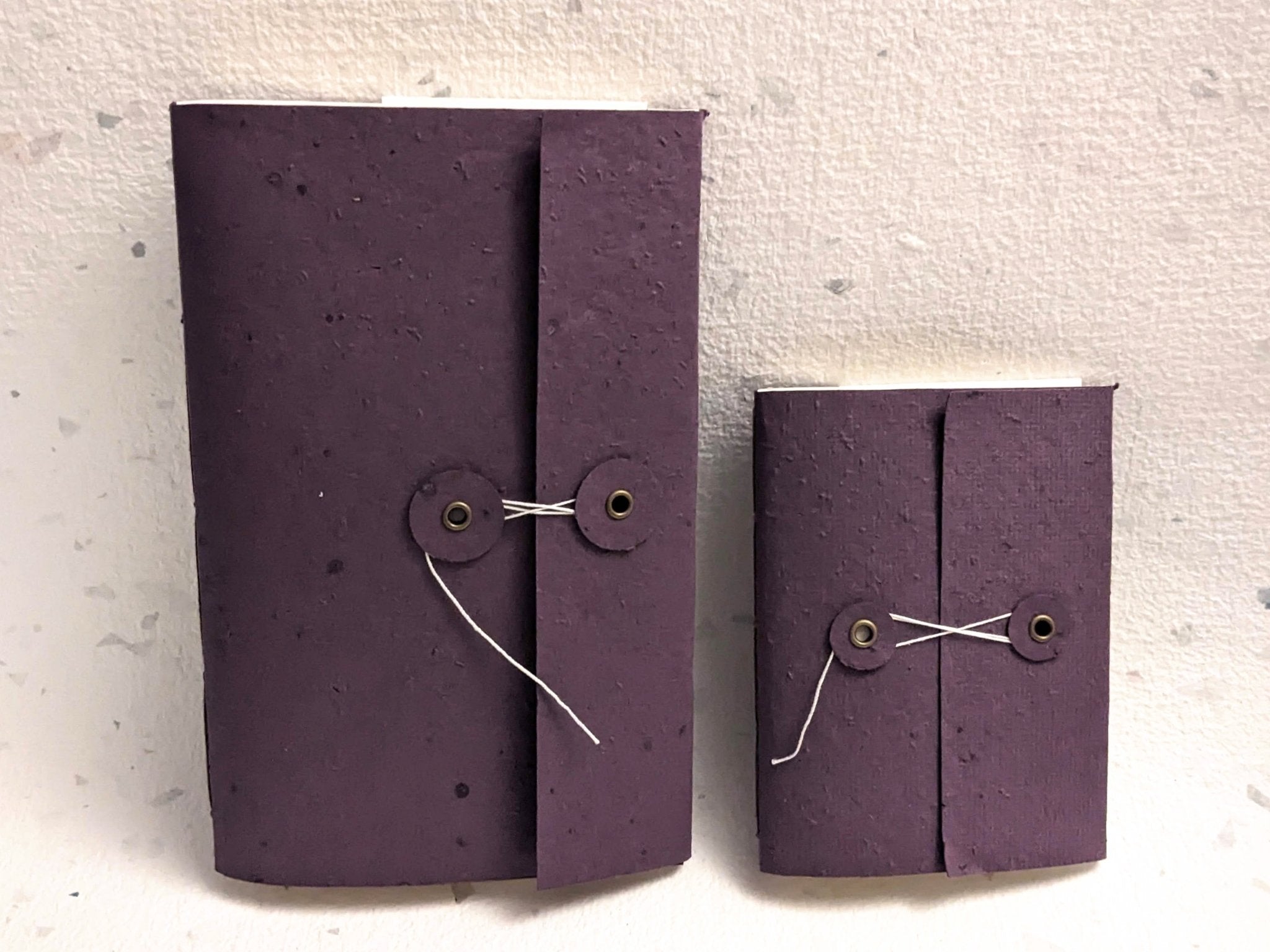 Two purple paper wallets with string closures on a textured white Creative Artifacts HQ plantable background