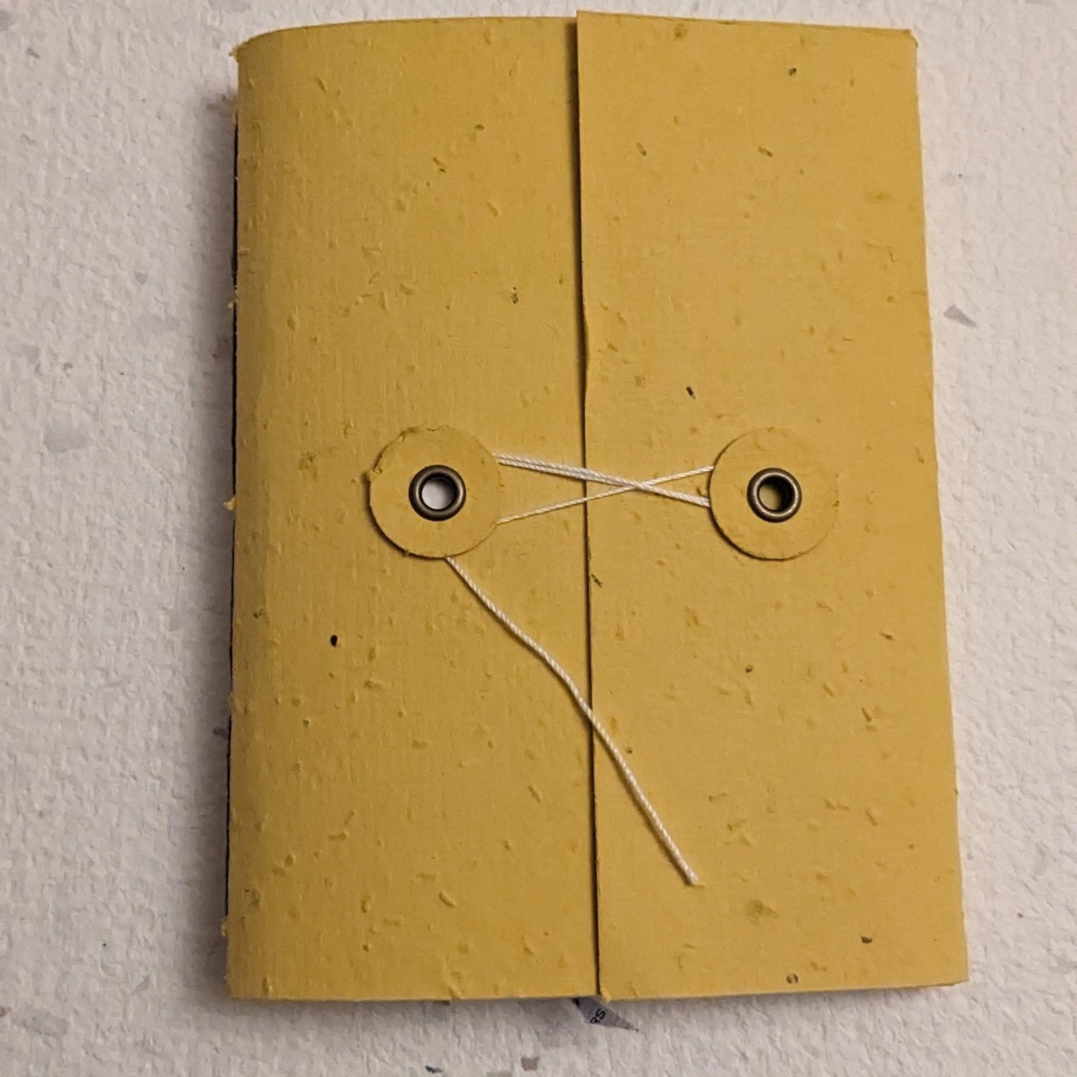 Yellow notebook with string hand stitched plantable paper notebook with string closure on a light grey background Creative Artifacts HQ