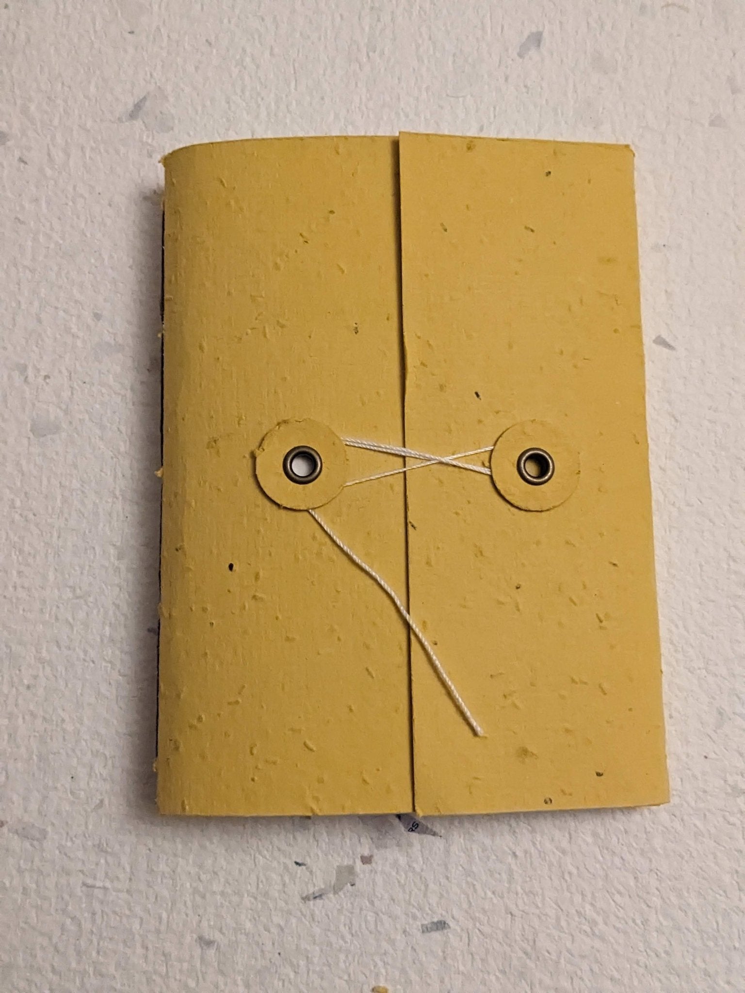 Yellow notebook with string hand stitched plantable paper notebook with string closure on a light grey background Creative Artifacts HQ