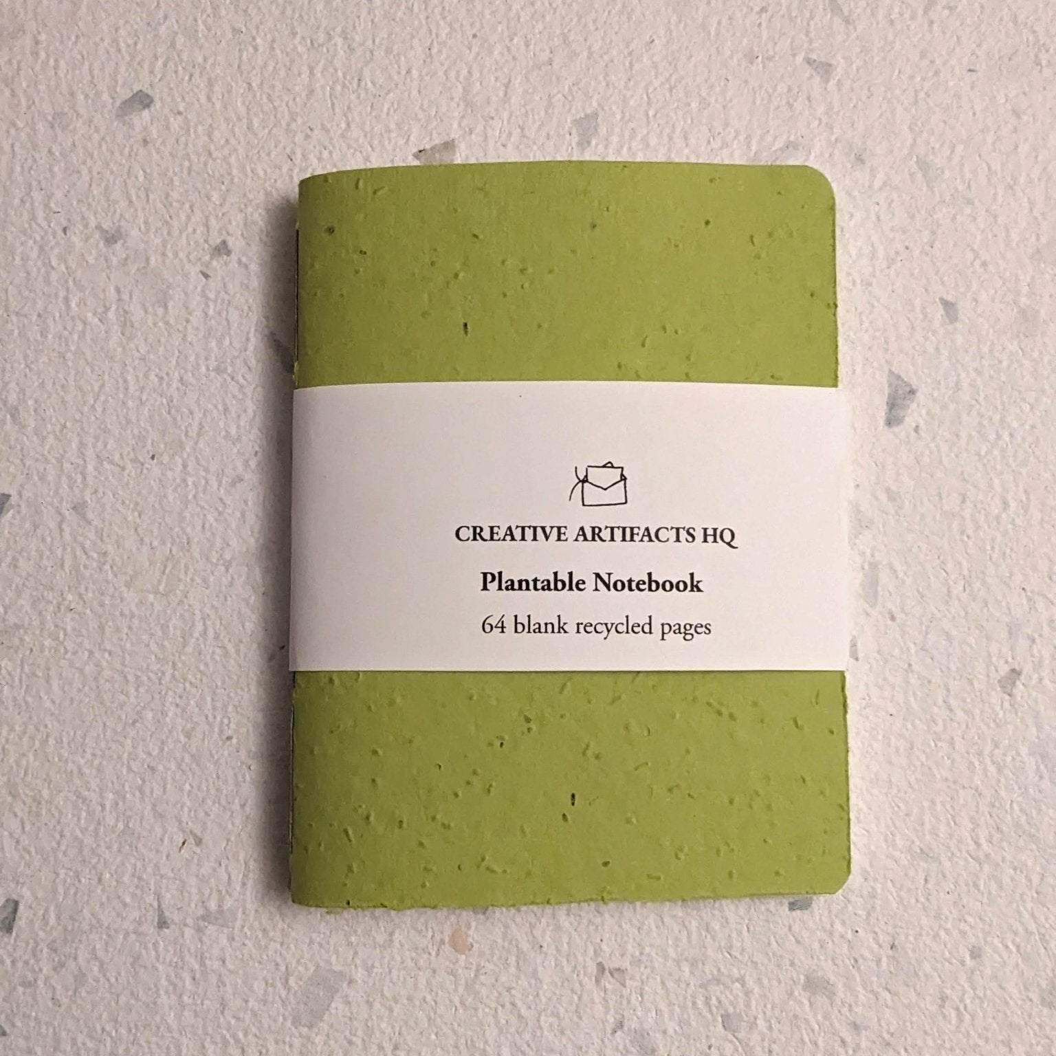 Green plantable notebook with a hand stitched plantable paper notebook on a light grey background Creative Artifacts HQ