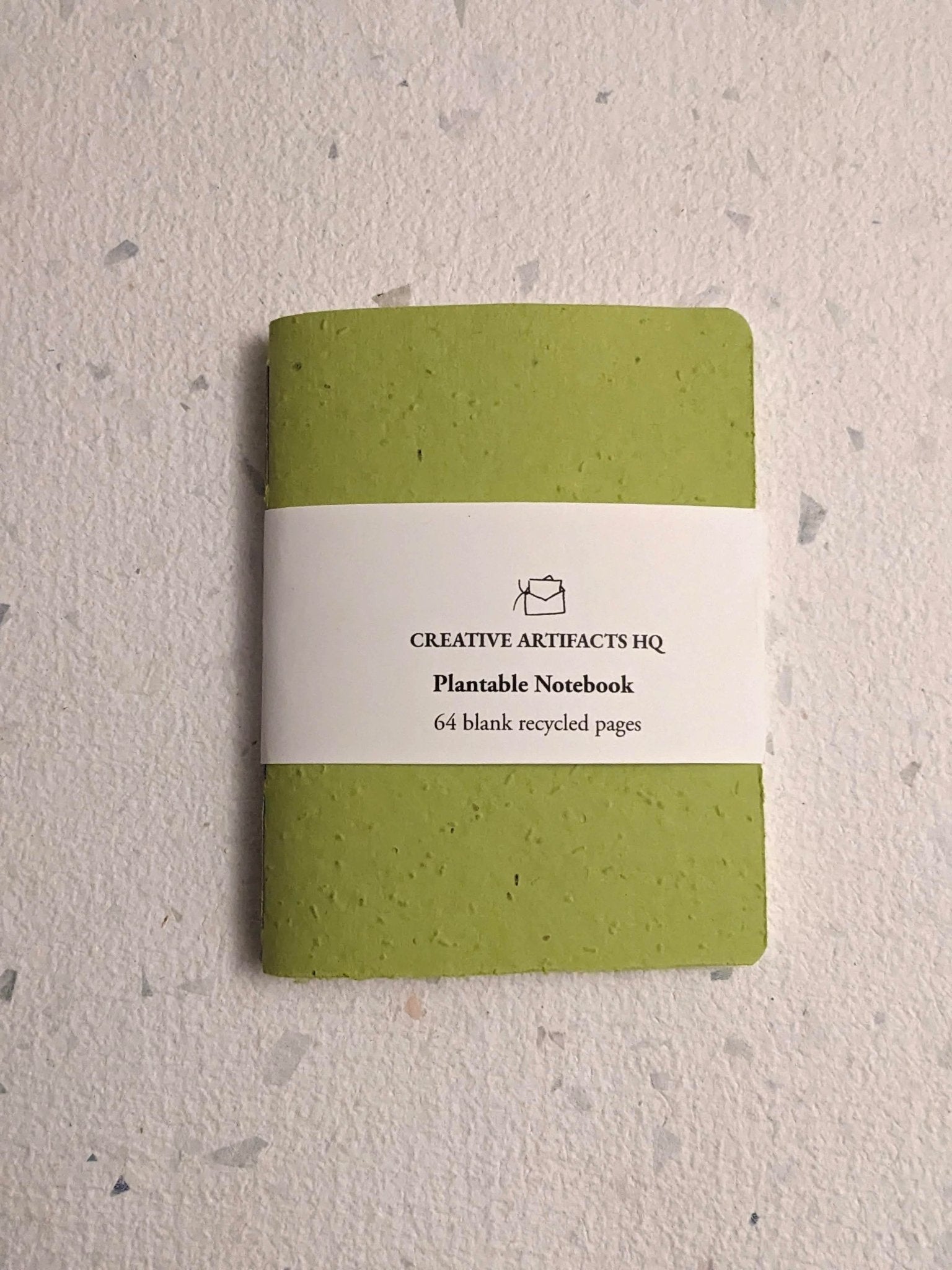 Green plantable notebook with a hand stitched plantable paper notebook on a light grey background Creative Artifacts HQ