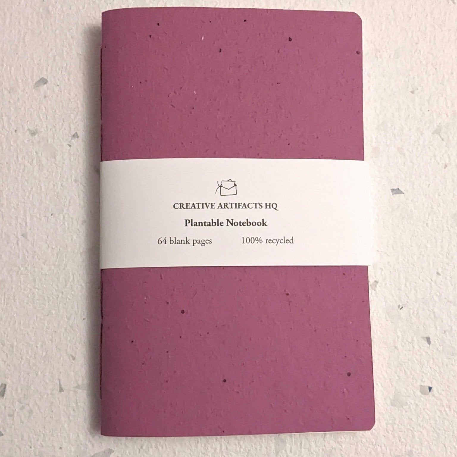 Purple notebook with a white label on a textured beige background Creative Artifacts HQ plantable handmade