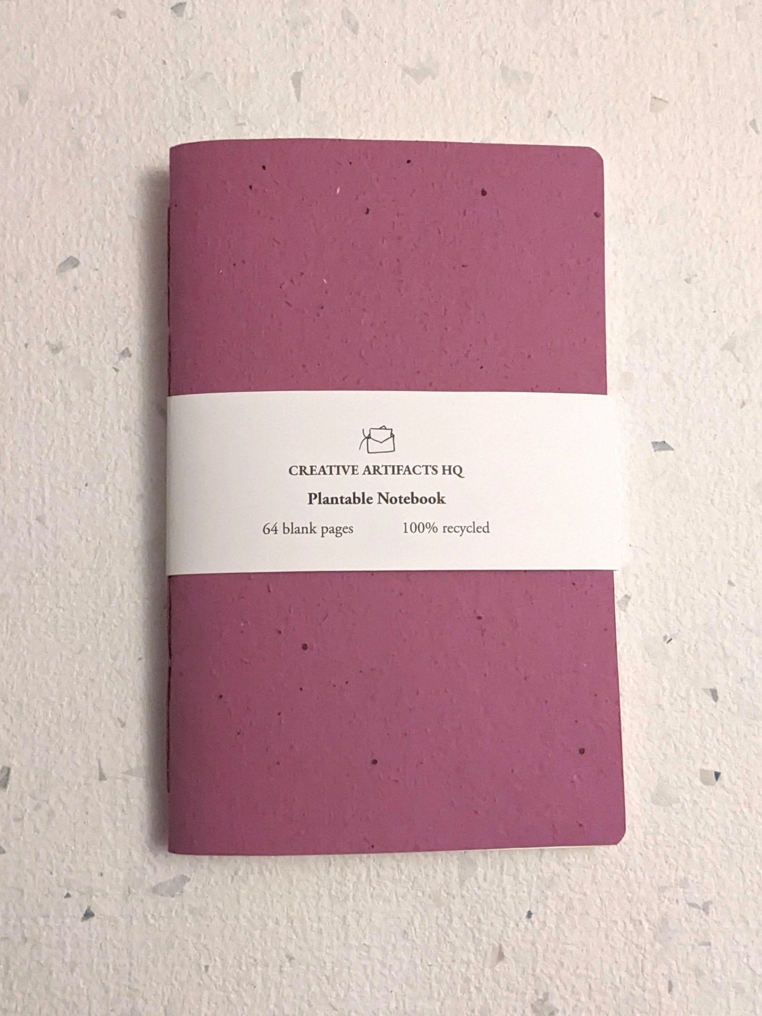 Purple notebook with a white label on a textured grey surface Creative Artifacts HQ plantable 