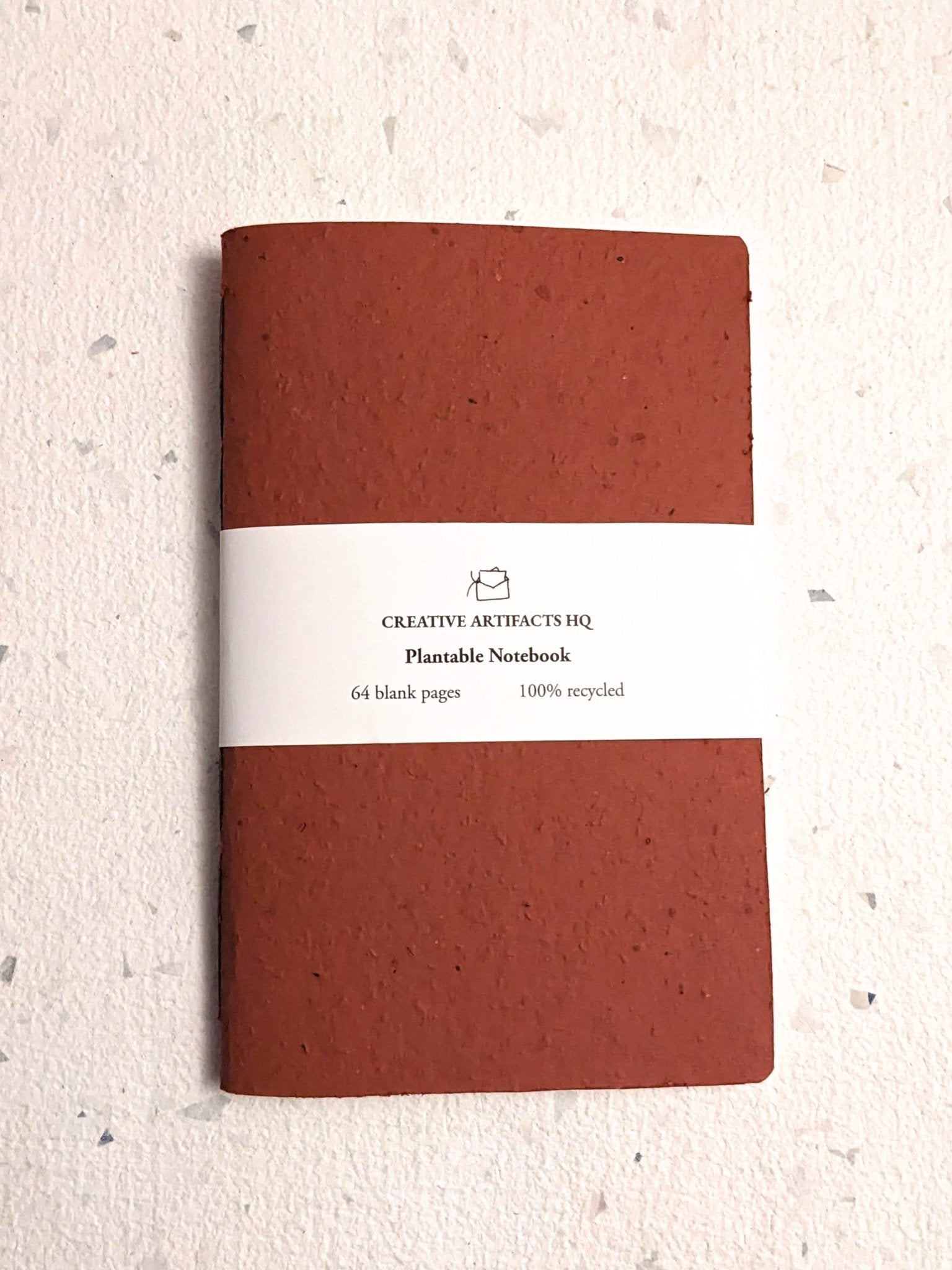 Brown notebook with a white label on a light grey surface Creative Artifacts HQ plantable 