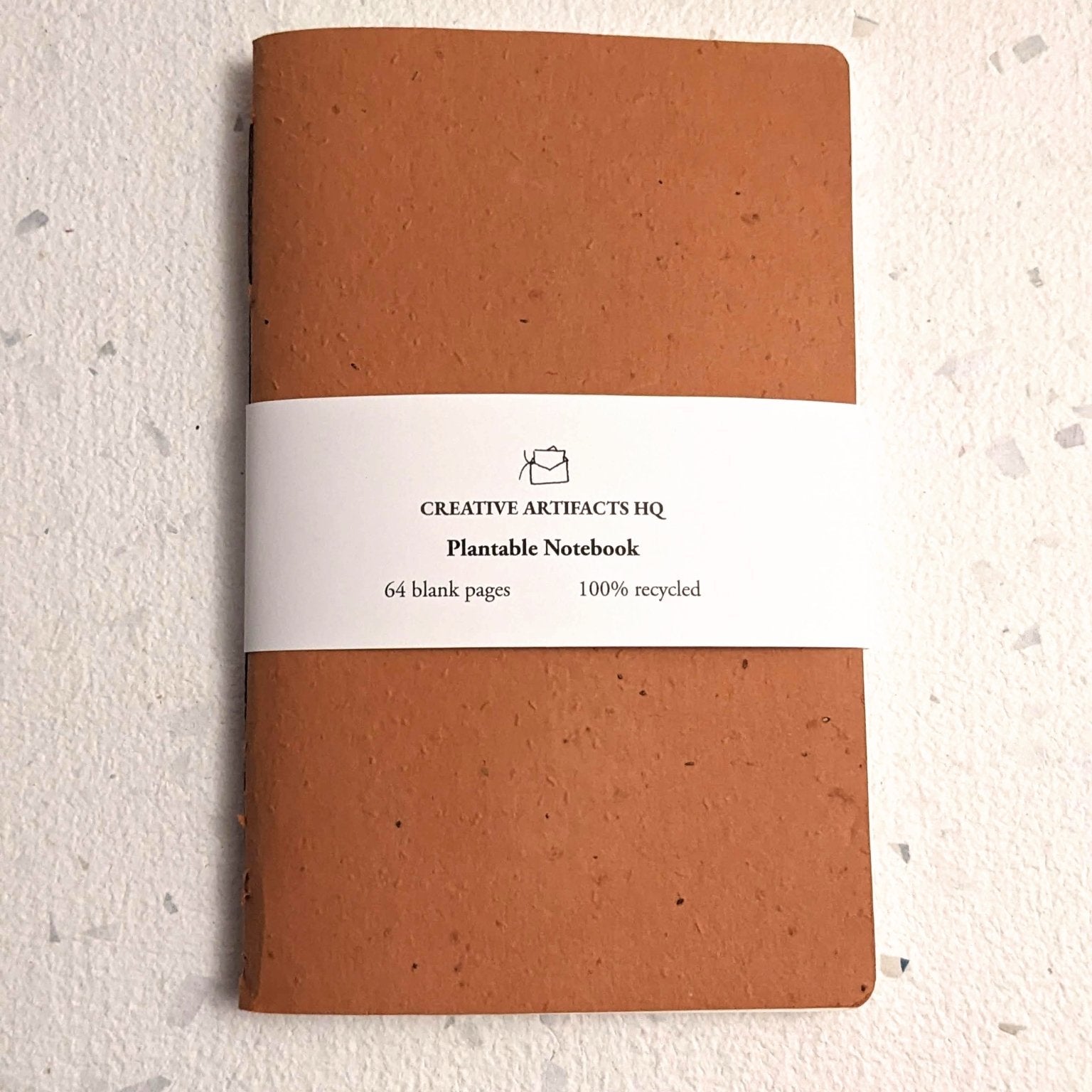 Brown notebook with a white label on a light beige background Creative Artifacts HQ plantable handmade
