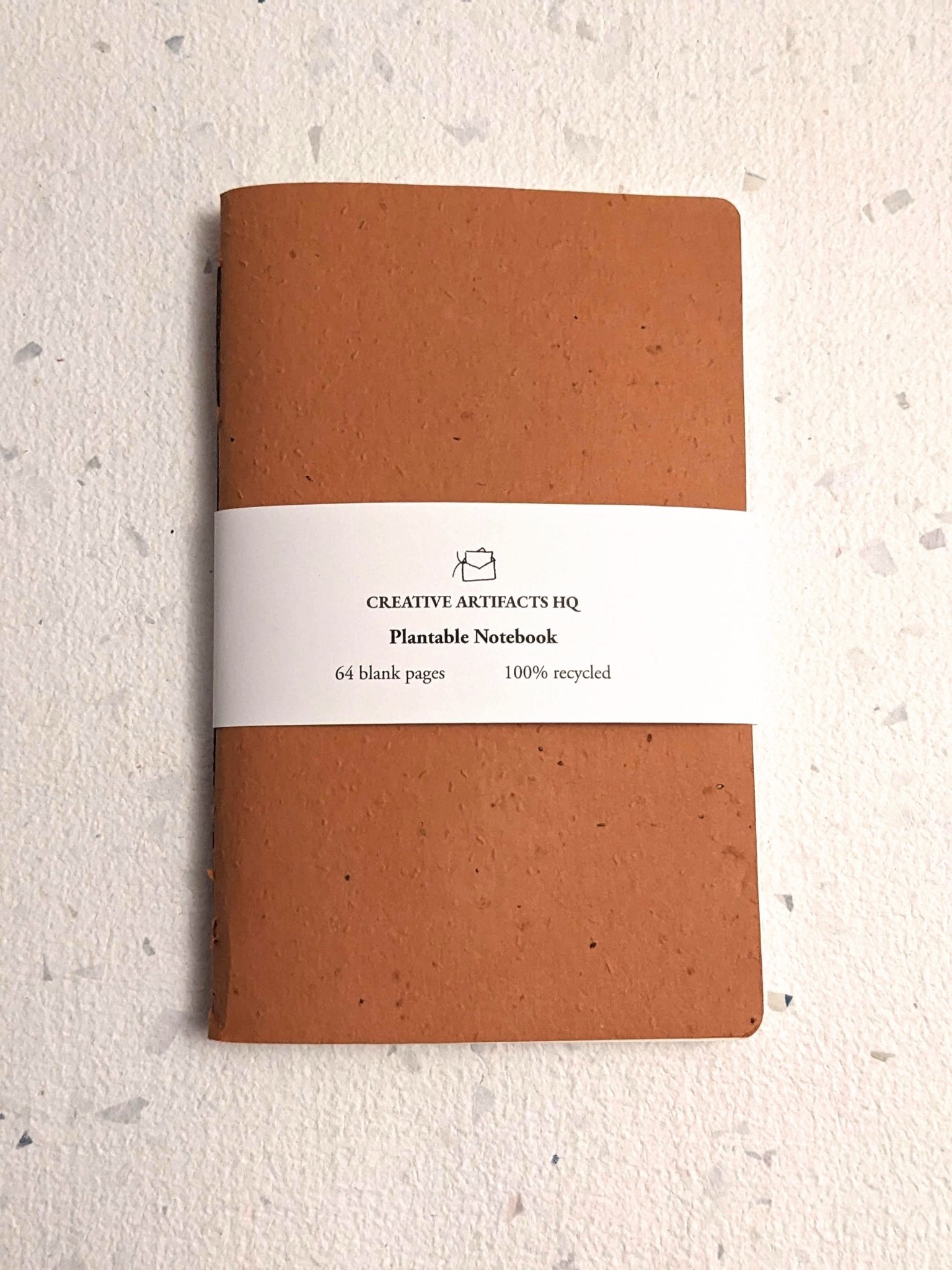 Brown notebook with a white label on a light grey surface Creative Artifacts HQ plantable 