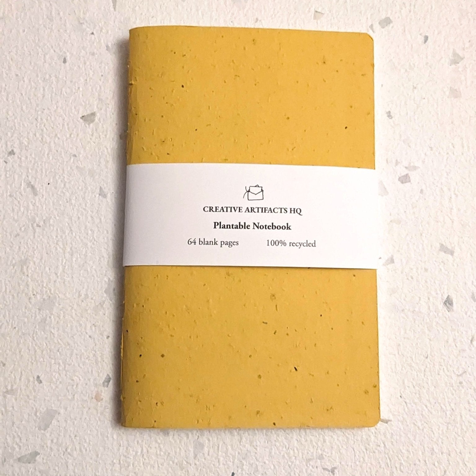 Yellow notebook with a white label on a light beige background Creative Artifacts HQ plantable handmade
