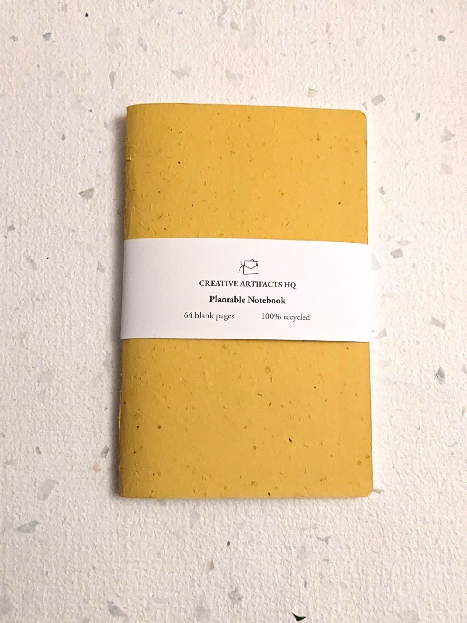 Yellow notebook with a white label on a light beige background Creative Artifacts HQ plantable handmade