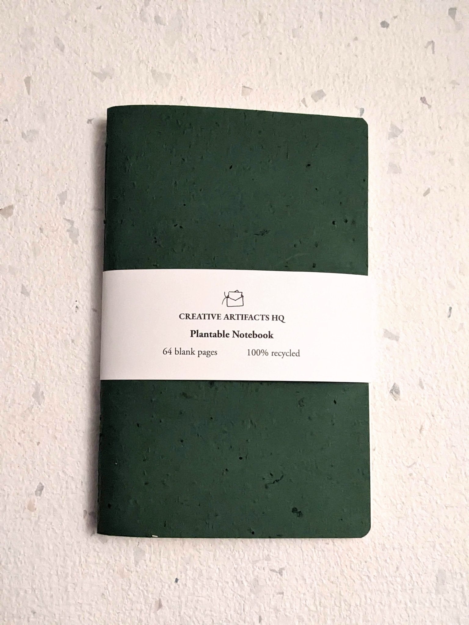 Green notebook with a label on a textured beige background Creative Artifacts HQ plantable handmade