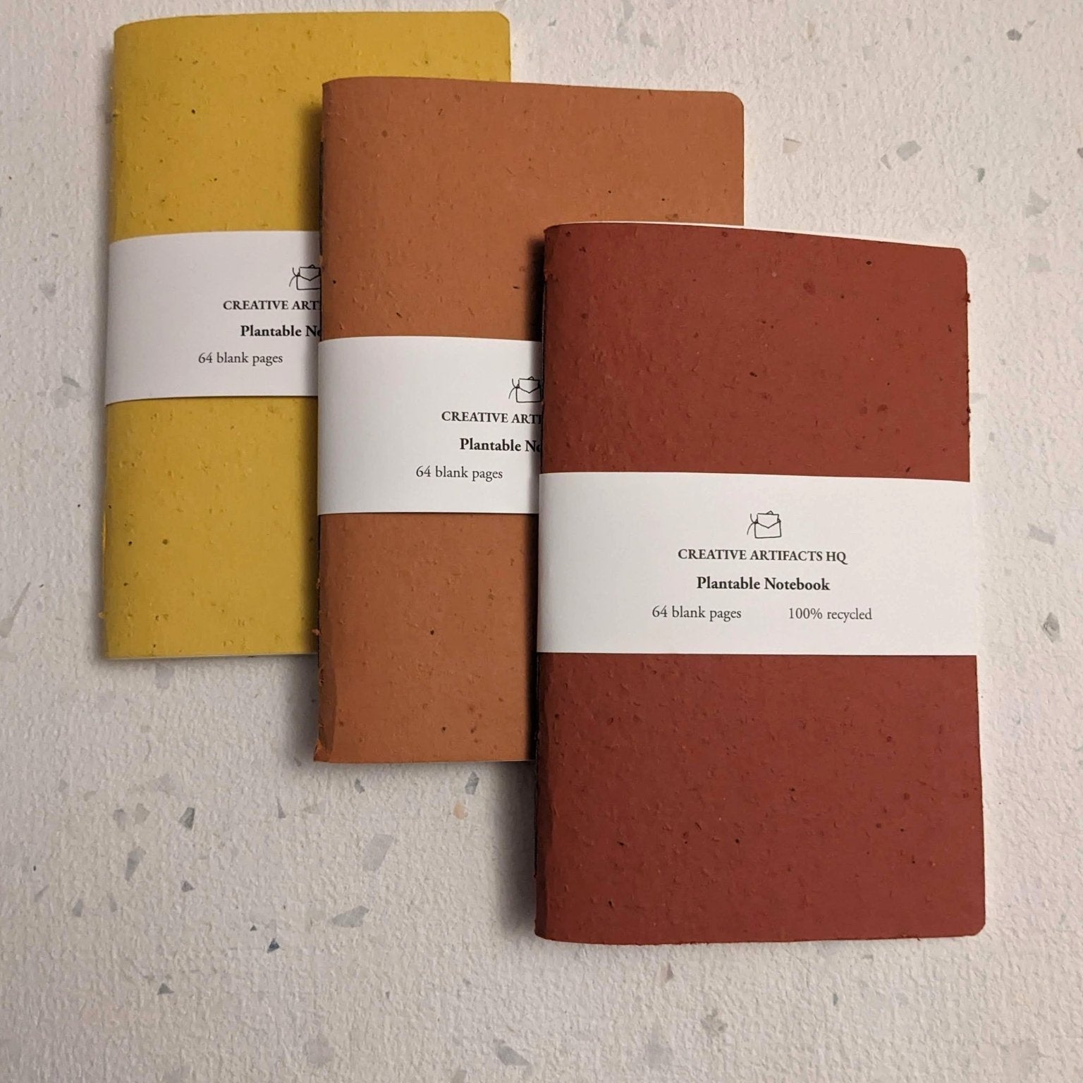 Three notebooks in yellow, orange, and red on a textured surface Creative Artifacts HQ plantable handmade