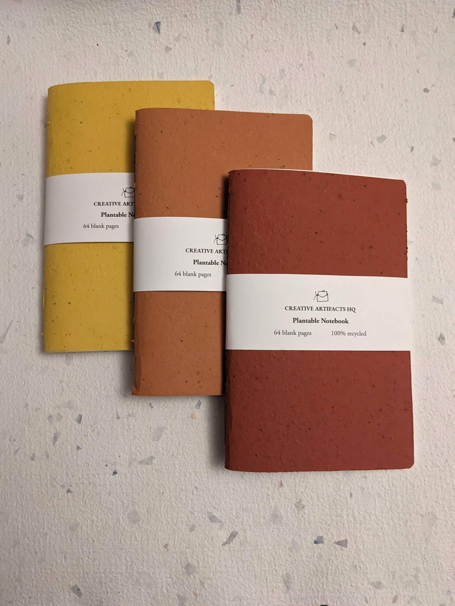 Three notebooks in yellow, orange, and red on a textured surface Creative Artifacts HQ plantable handmade