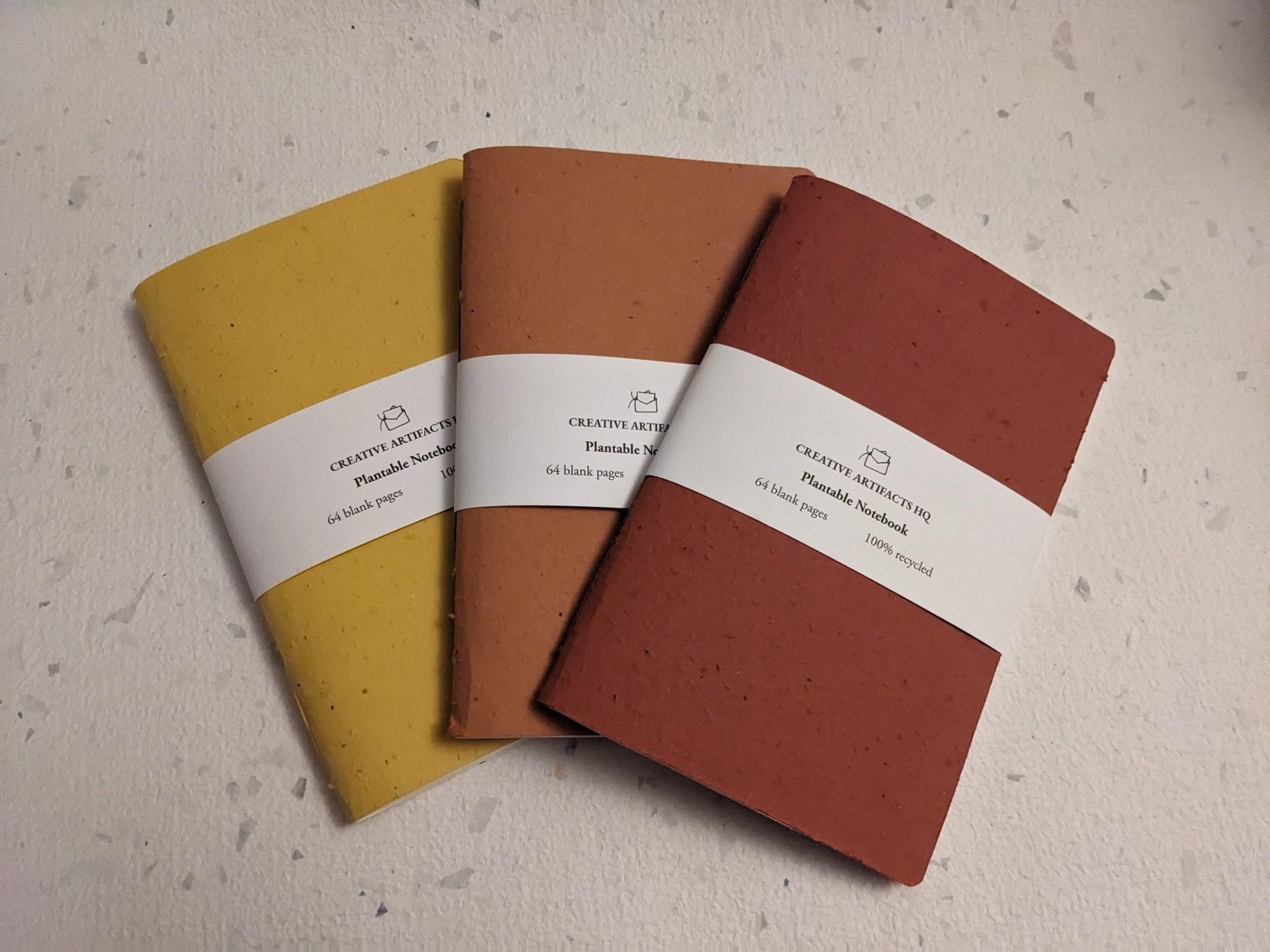 Three notebooks in yellow, orange, and red on a textured surface Creative Artifacts HQ plantable handmade