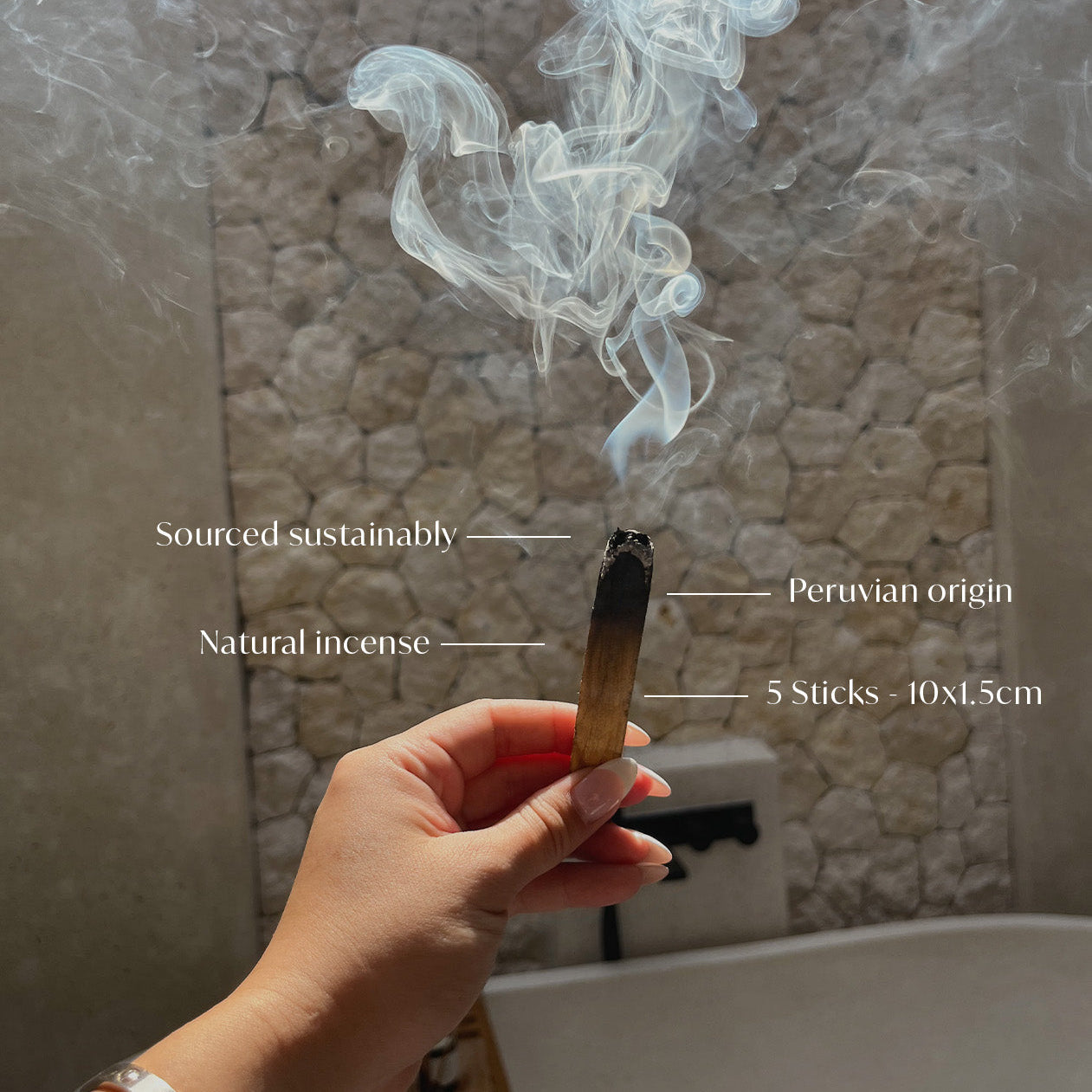 Hand holding a smoking incense stick with text labels against a textured wall background