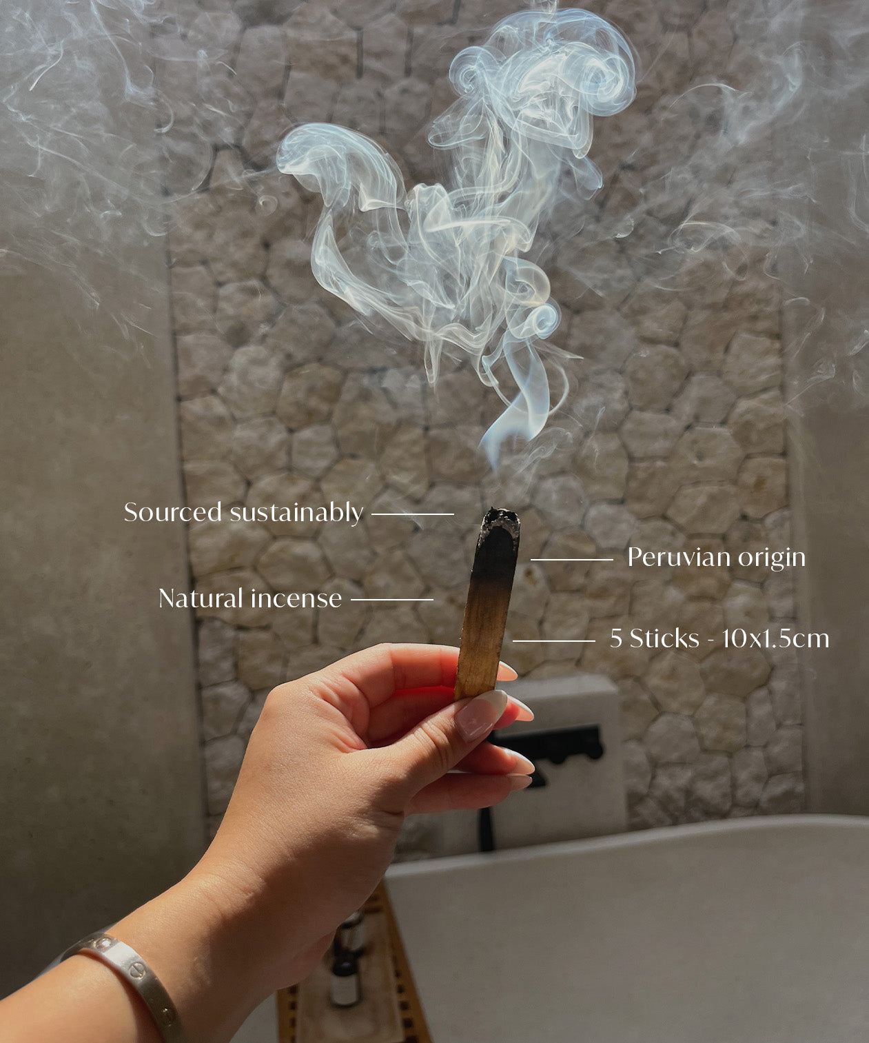 Hand holding a smoking incense stick with text labels against a textured wall background