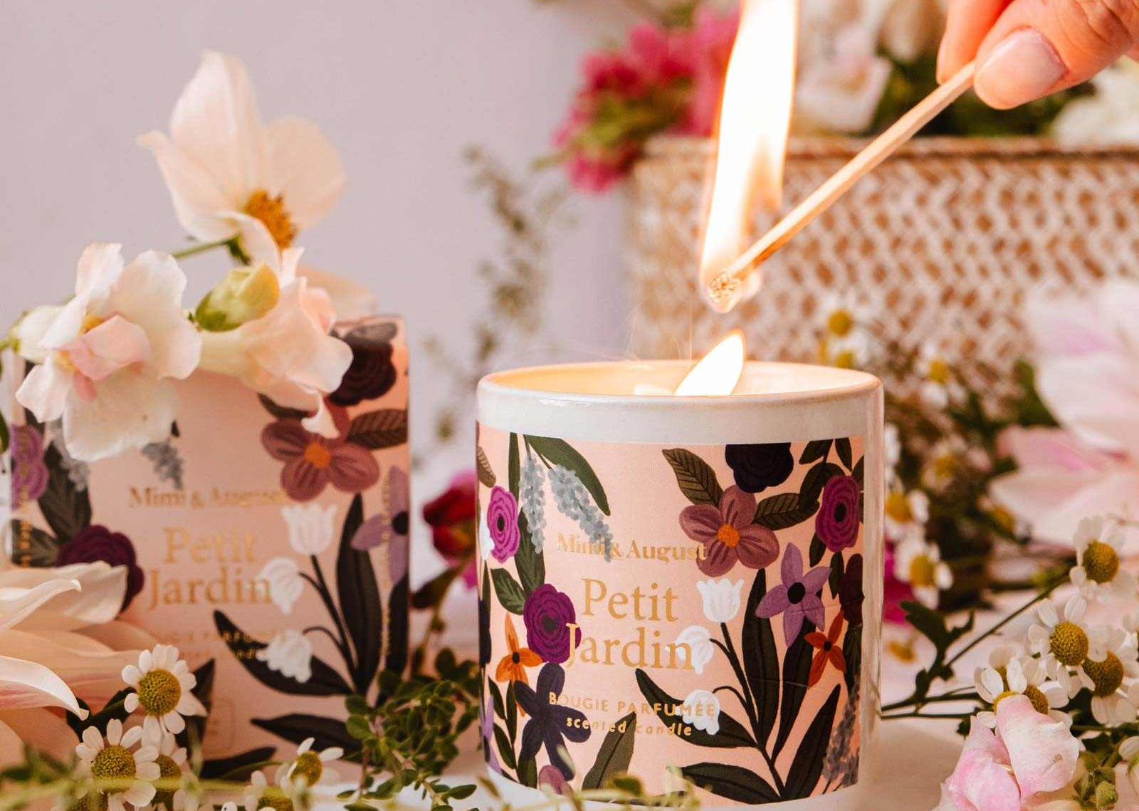 Candle being lit with floral design, surrounded by flowers and a woven basket.