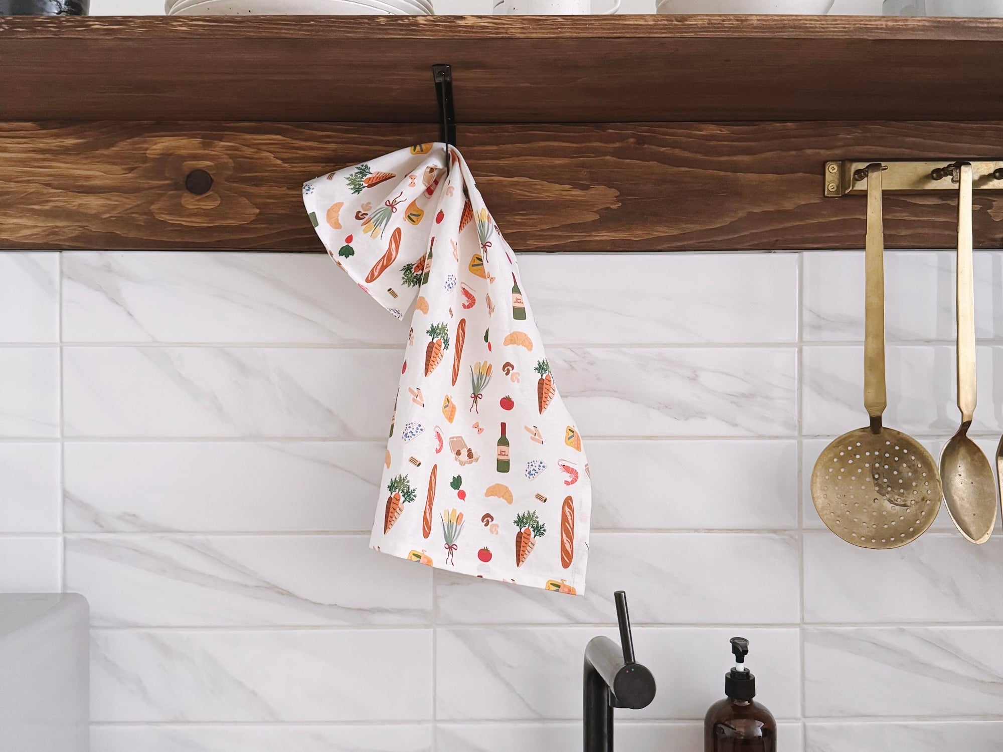 Kitchen with wooden shelf, white tiles, and a sink with a towel and bottles.