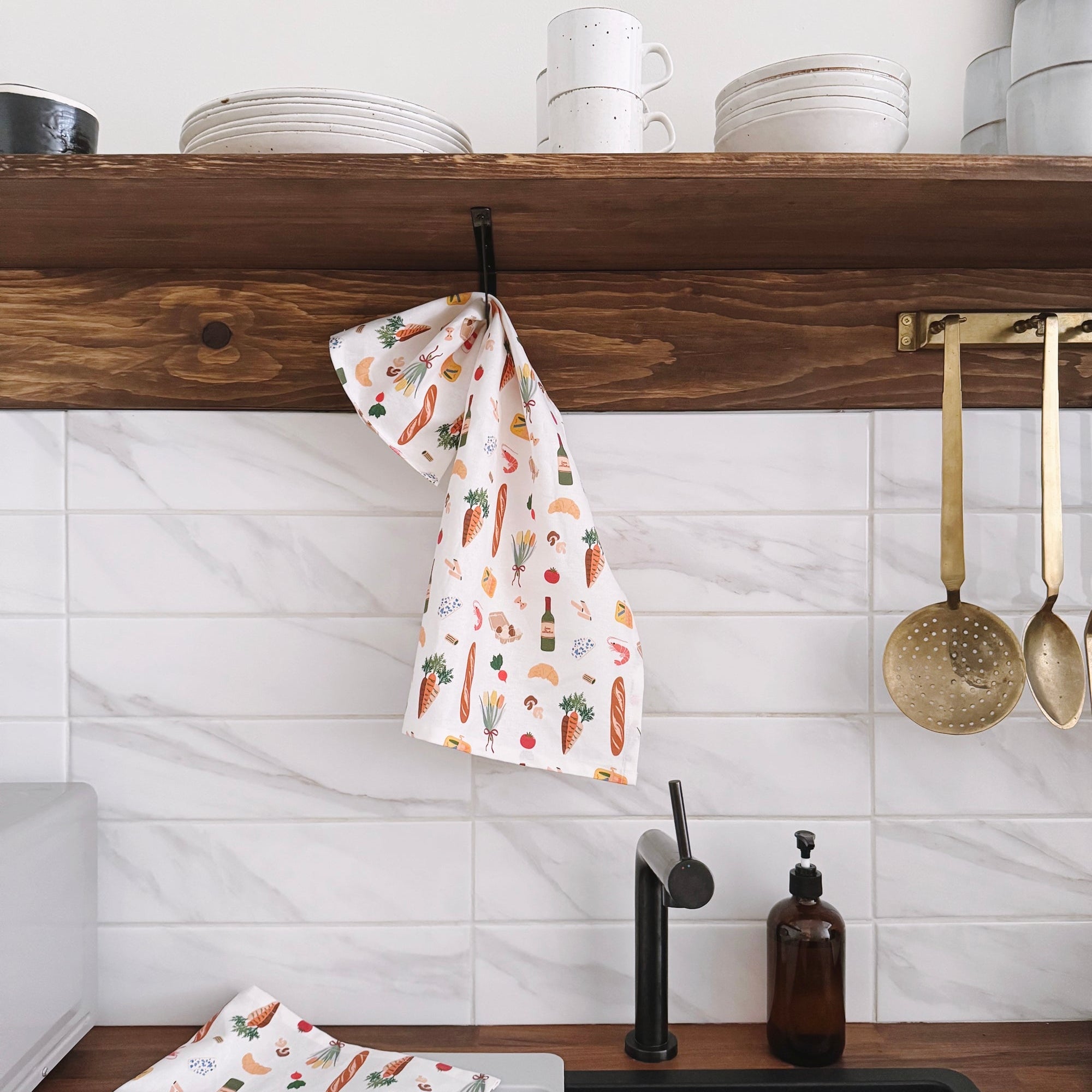 Kitchen with wooden shelf, white tiles, and a sink with a towel and bottles.