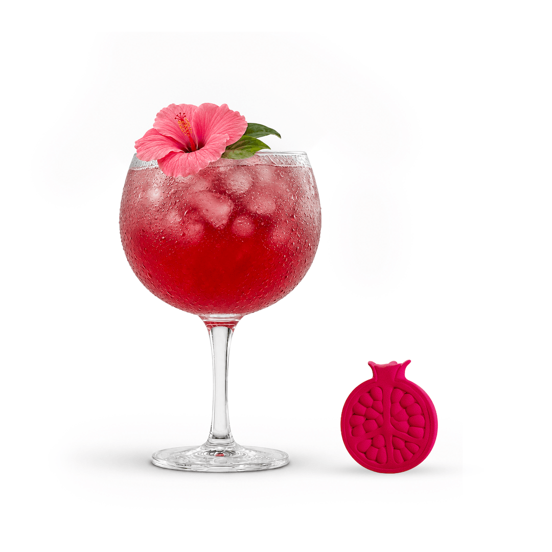 Red cocktail in a glass with a pink flower and a pink pomegranate-shaped coaster on a white background
